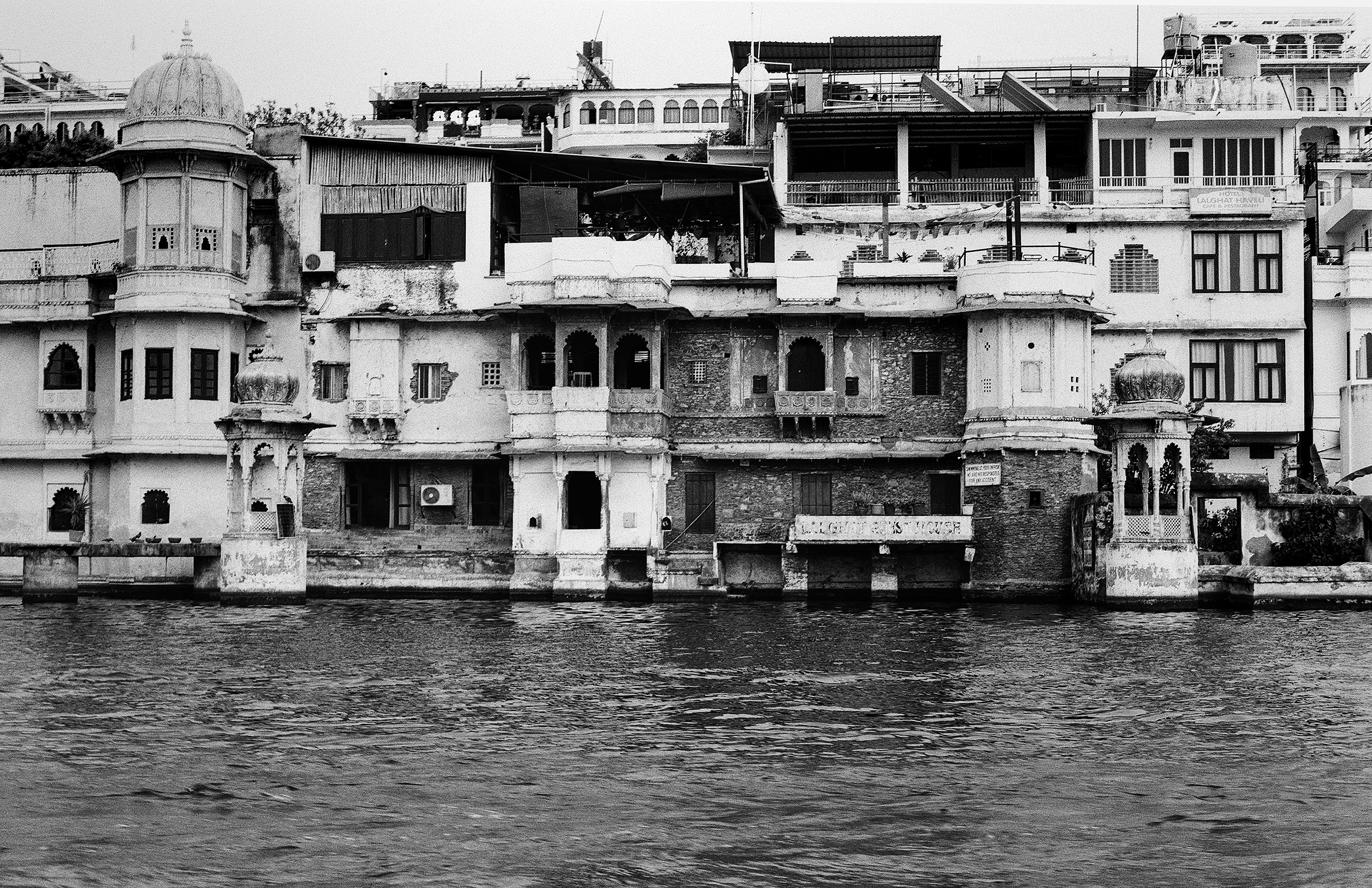 Black and white waterfront buildings along Lake Pichola with domed towers and multi-story structures