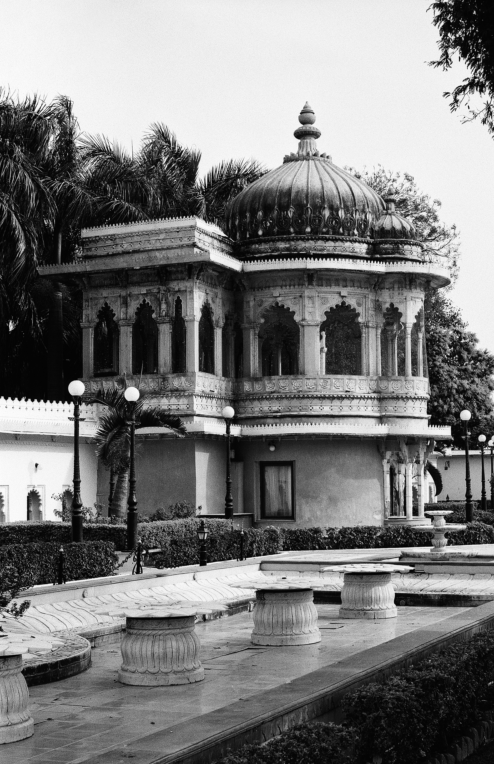Black and white ornate domed pavilion in formal garden with palm trees and fountain pedestals