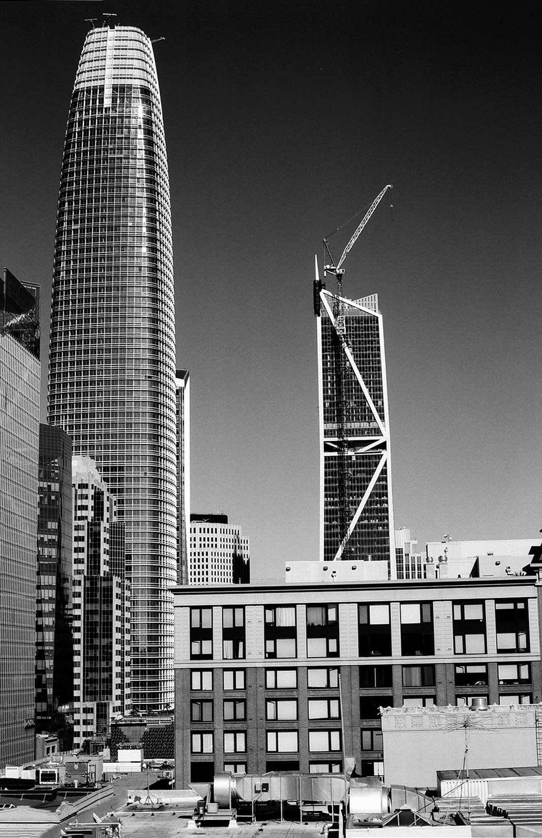Iconic modernist towers including Transamerica Tower with angular steel braces construction cranes and clear sky showcasing San Francisco architecture