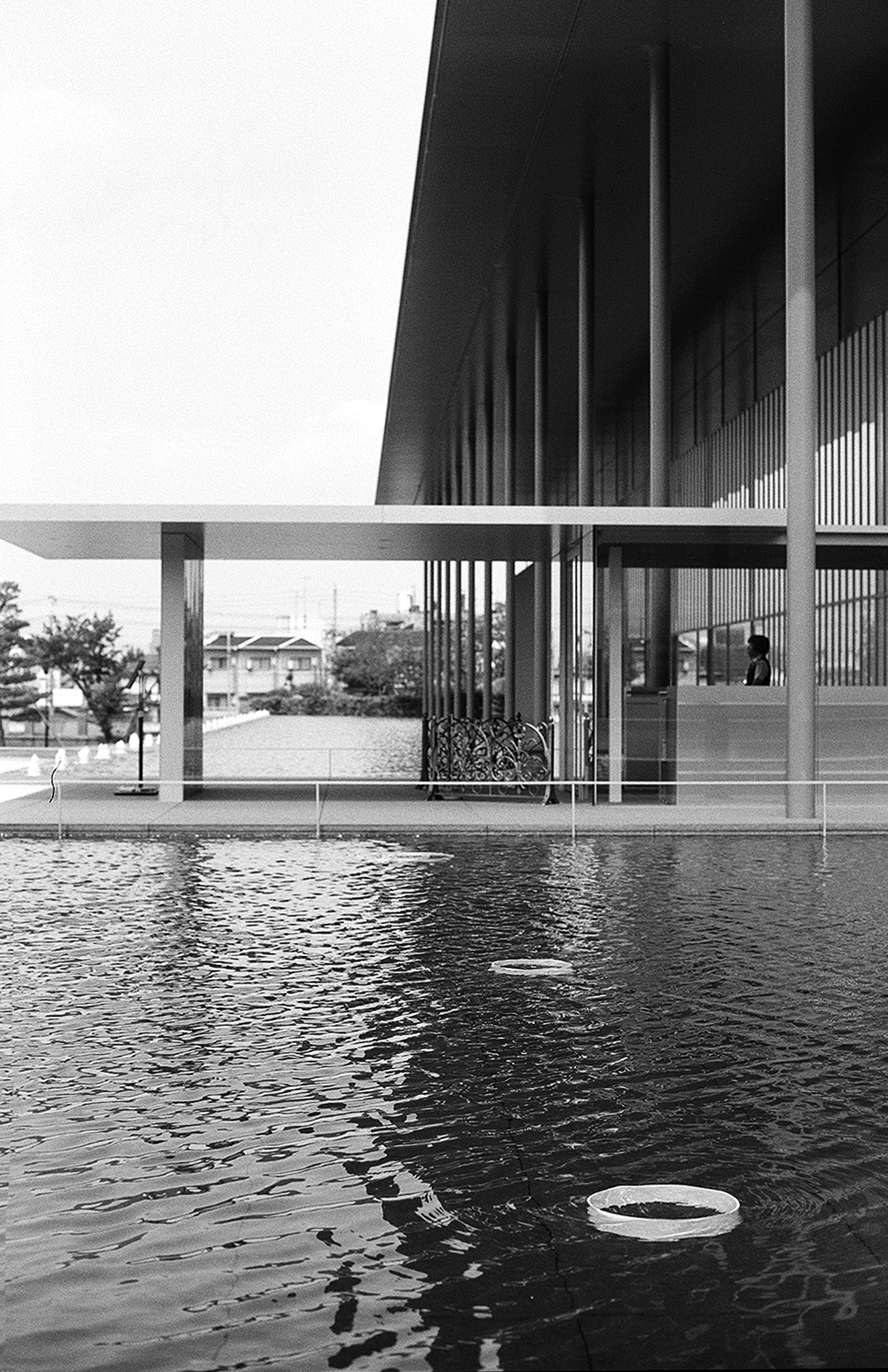 Contemporary architectural pool reflecting building with horizontal lines vertical columns and bamboo bicycle detail