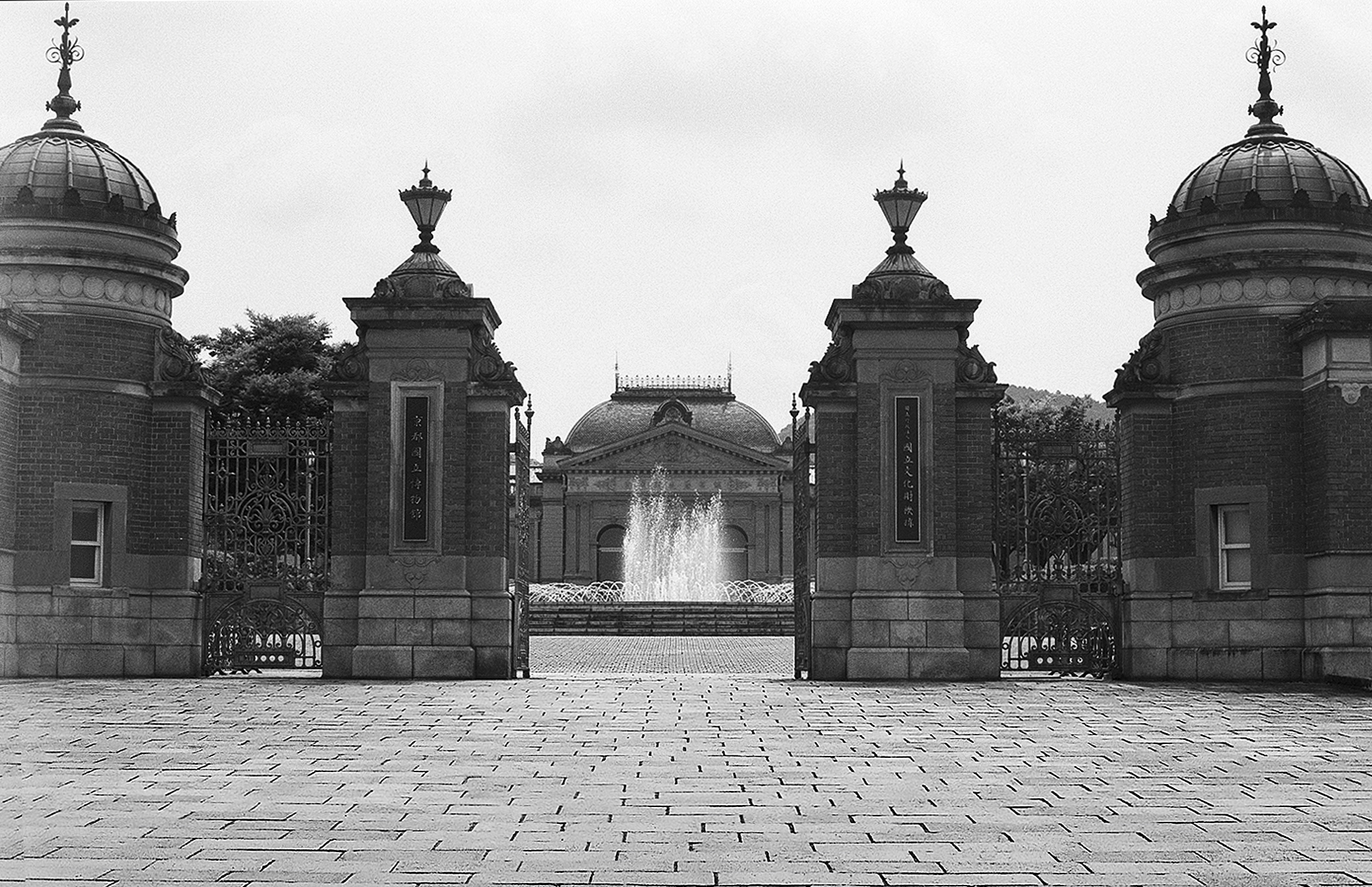 Symmetrical neoclassical ornamental gateway with paired domed pavilion structures flanking fountain and plaza