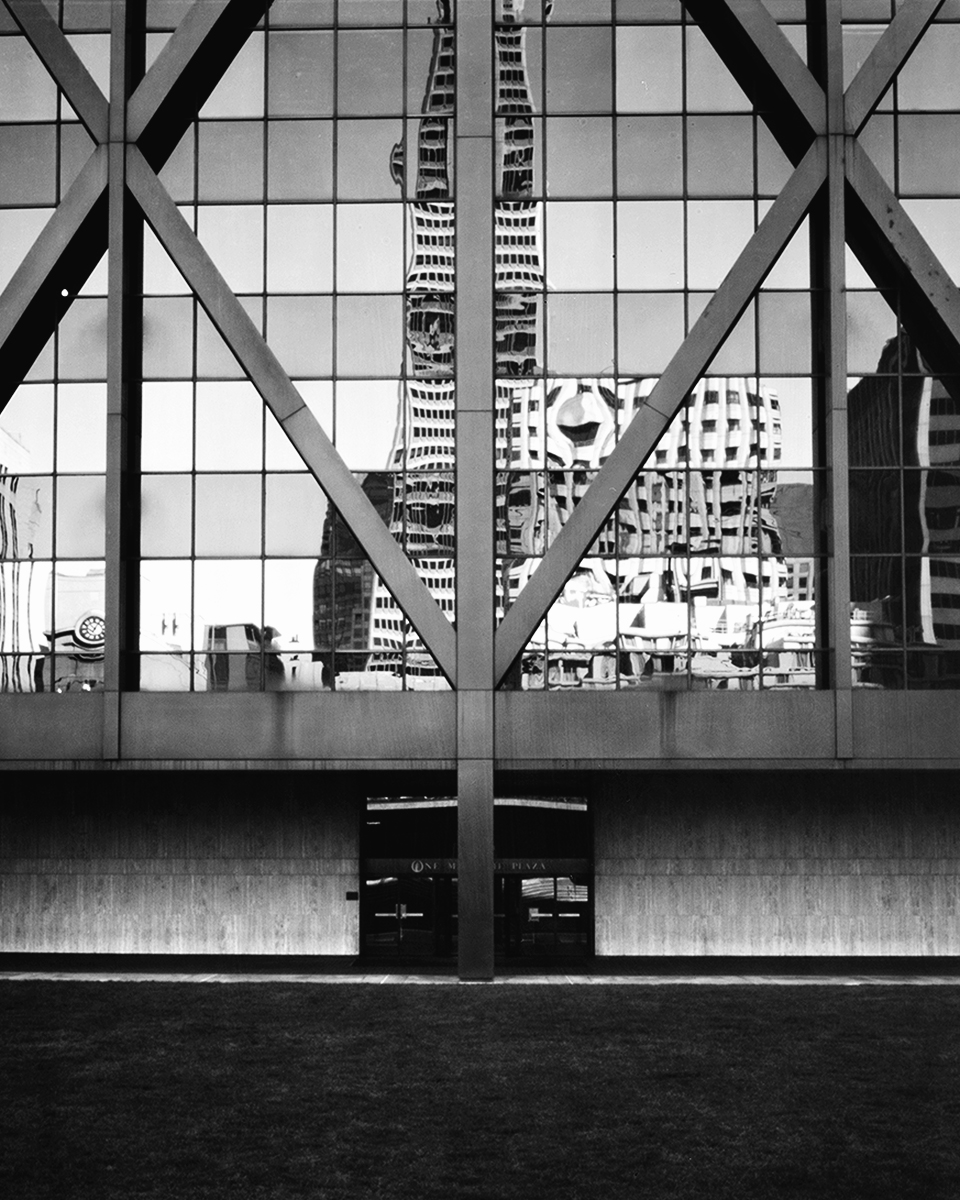 View through geometric X-patterned window frame showing Transamerica Pyramid and San Francisco downtown skyline