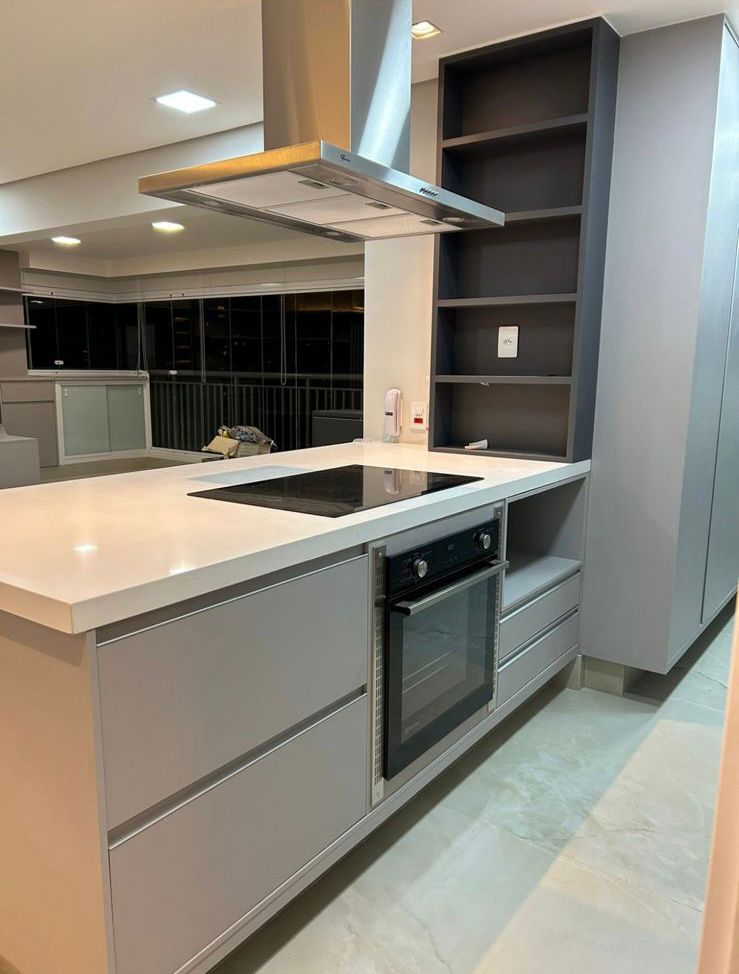 Cozinha planejada cinza com ilha, cooktop e forno embutido