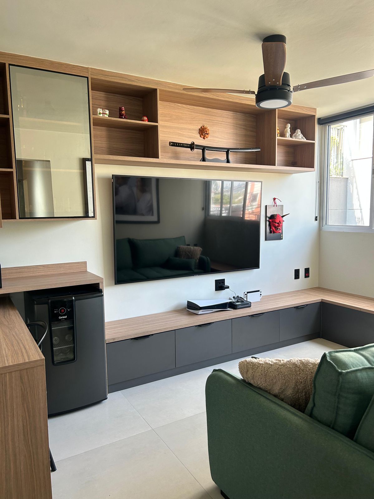 Sala de estar com painel de TV em madeira e sofá verde