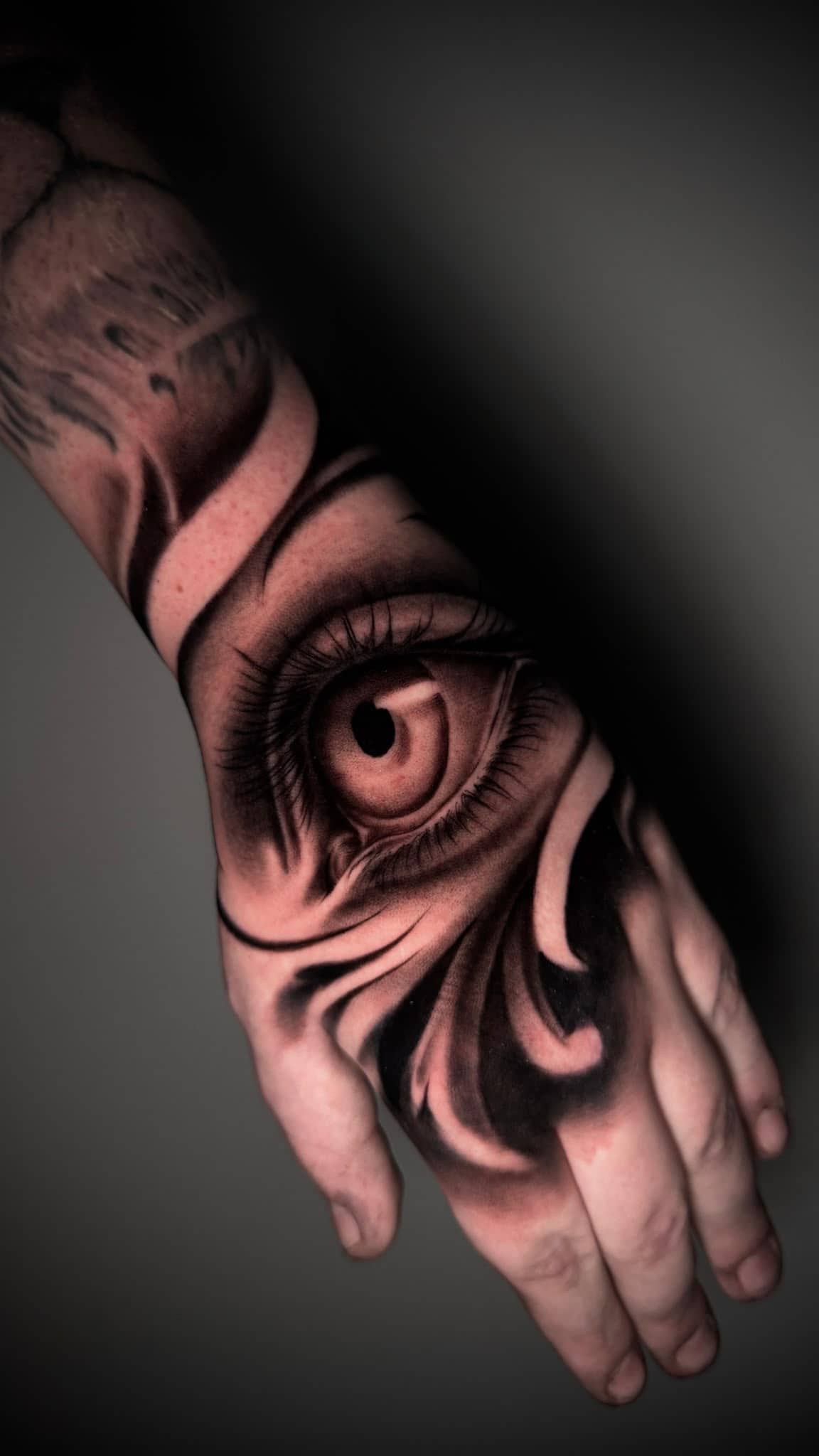 Black and Grey realistisches Auge auf Handruecken mit Wirbel-Muster