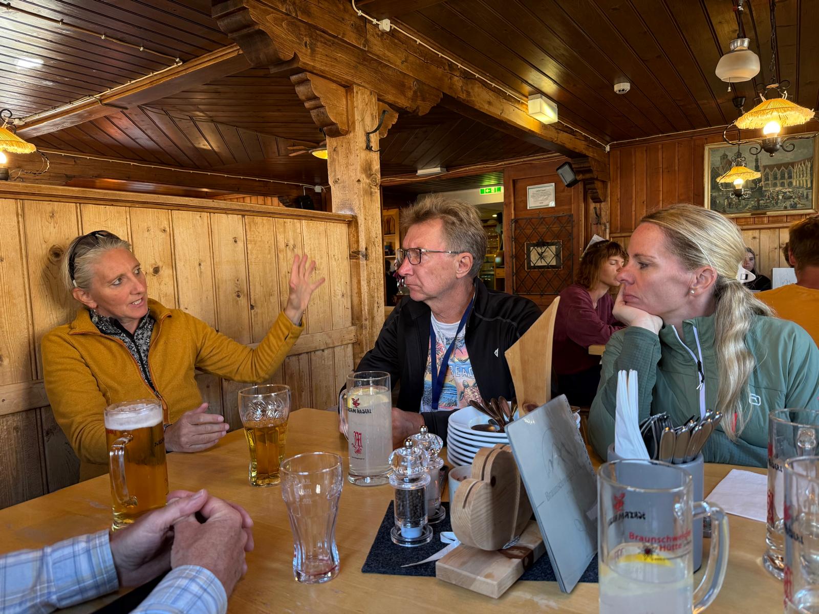 Teilnehmer im Gespräch an einem Tisch in einer Berghütte
