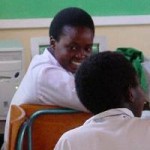 Schülerin im weißen Hemd lächelt in der Klasse