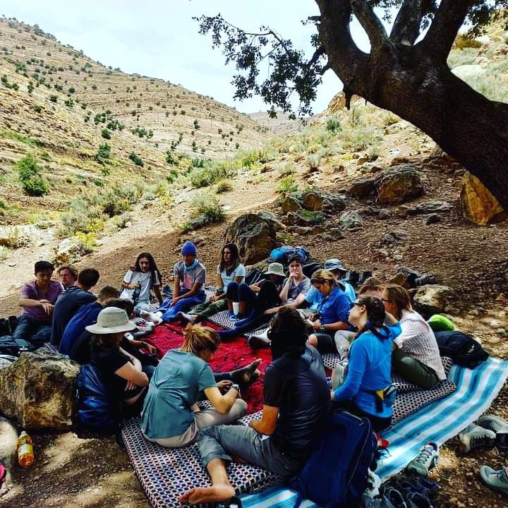 Group of hikers sharing a meal together under a large tree on the mountain