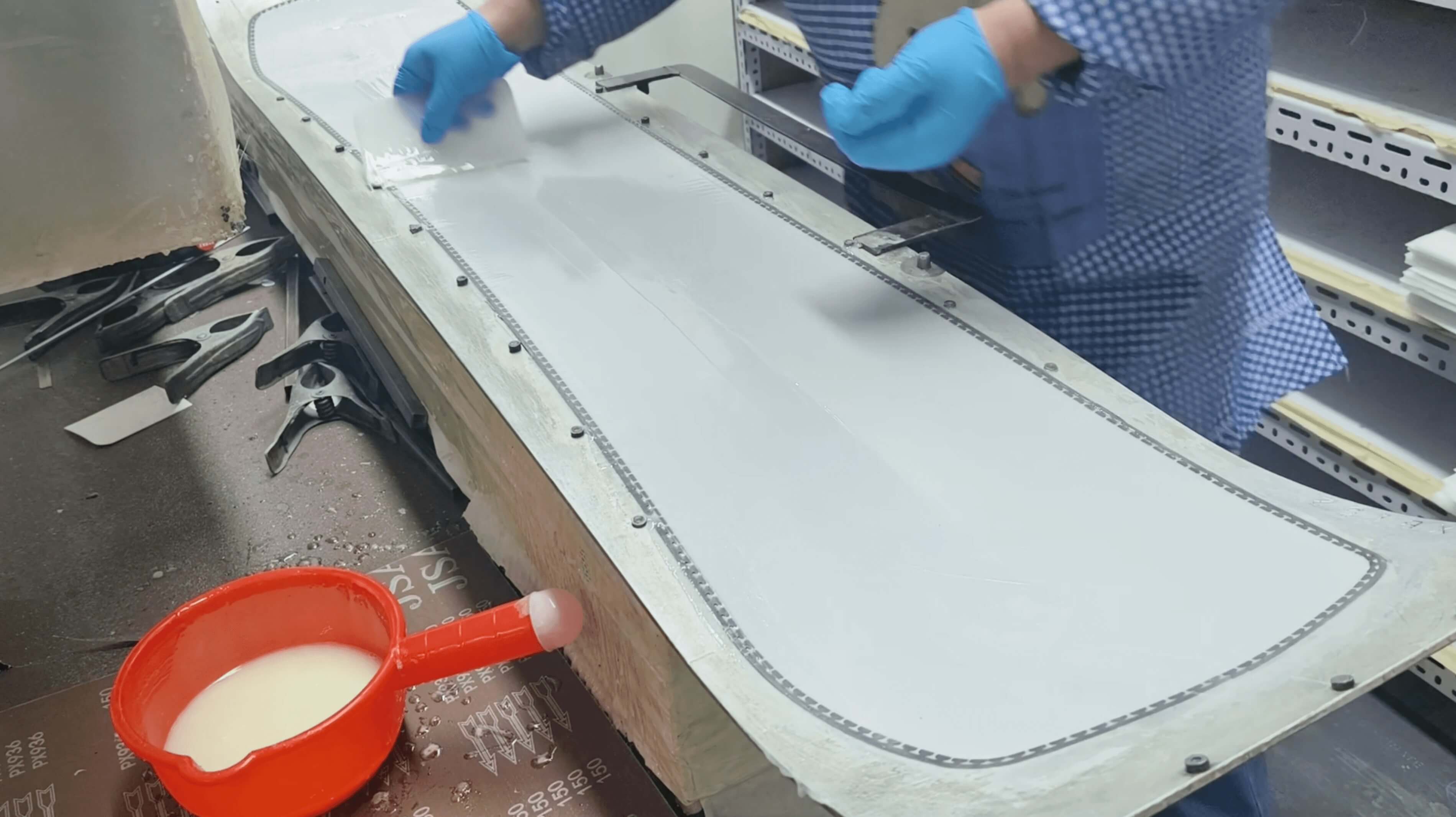 Technician laying fiberglass over sintered base inside the press mold