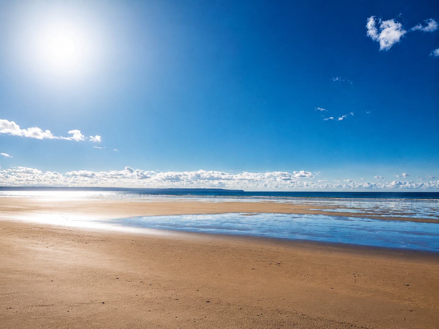 Wide empty sandy beach on the North Devon coast under a vivid blue sky