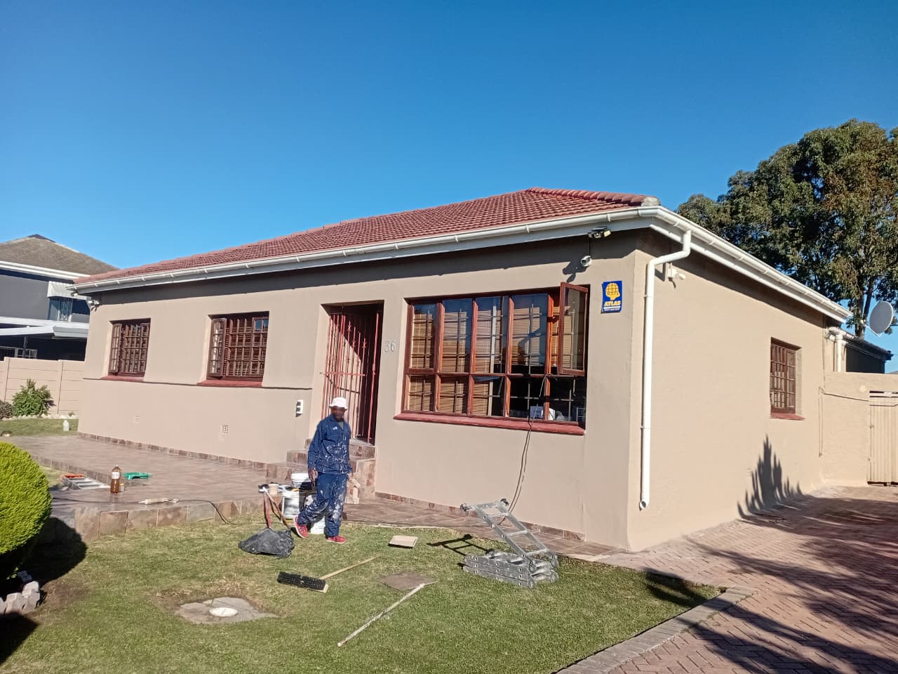 After: Beautifully painted cream exterior with clean finish, burgundy window frames, and red tile roof