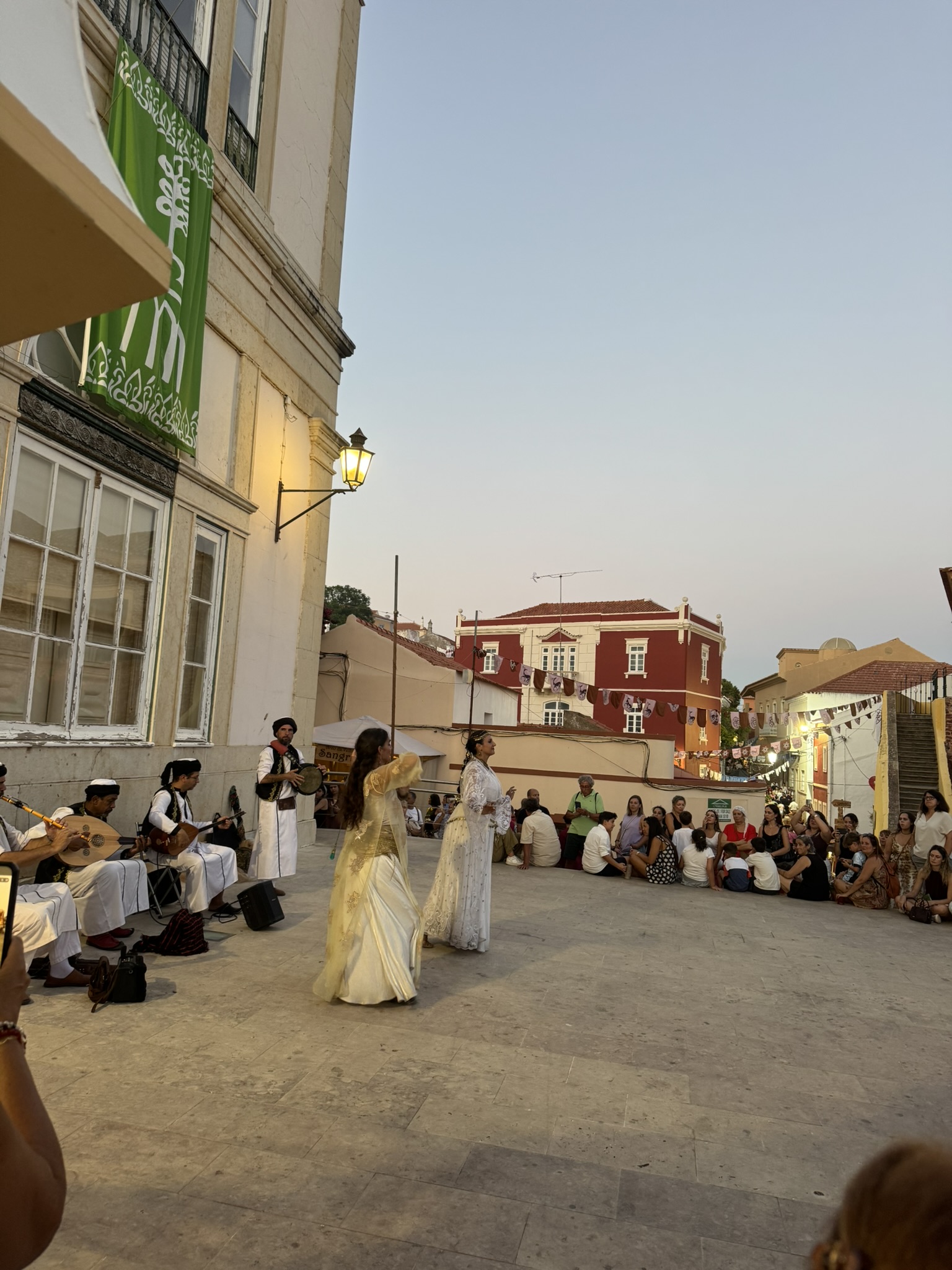Musicians and dancers in traditional dress performing in a Silves square at dusk