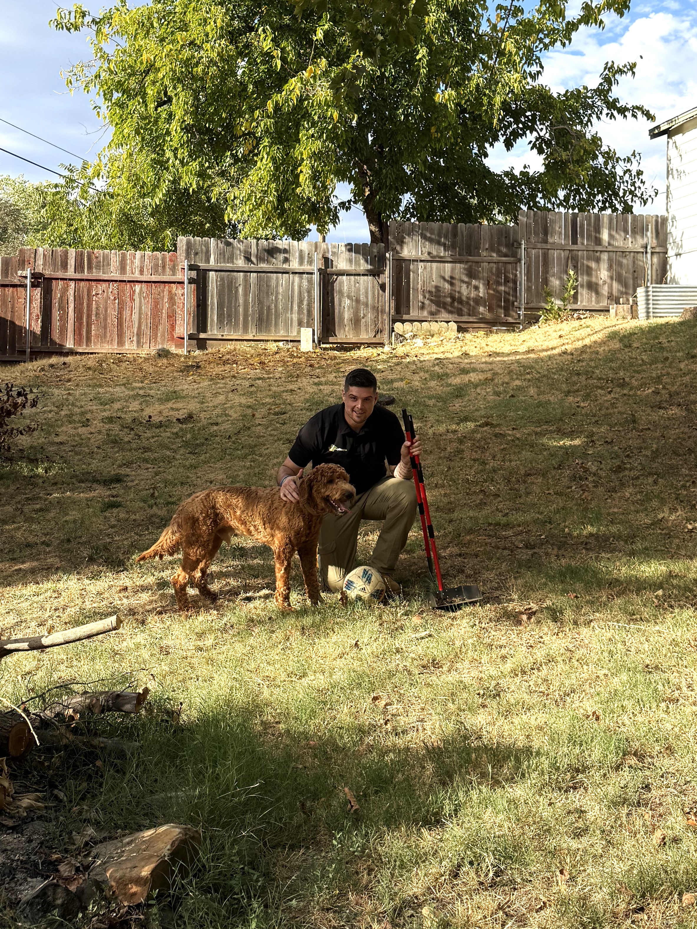 Poop Scoop Co. owner posing with a dog in a backyard