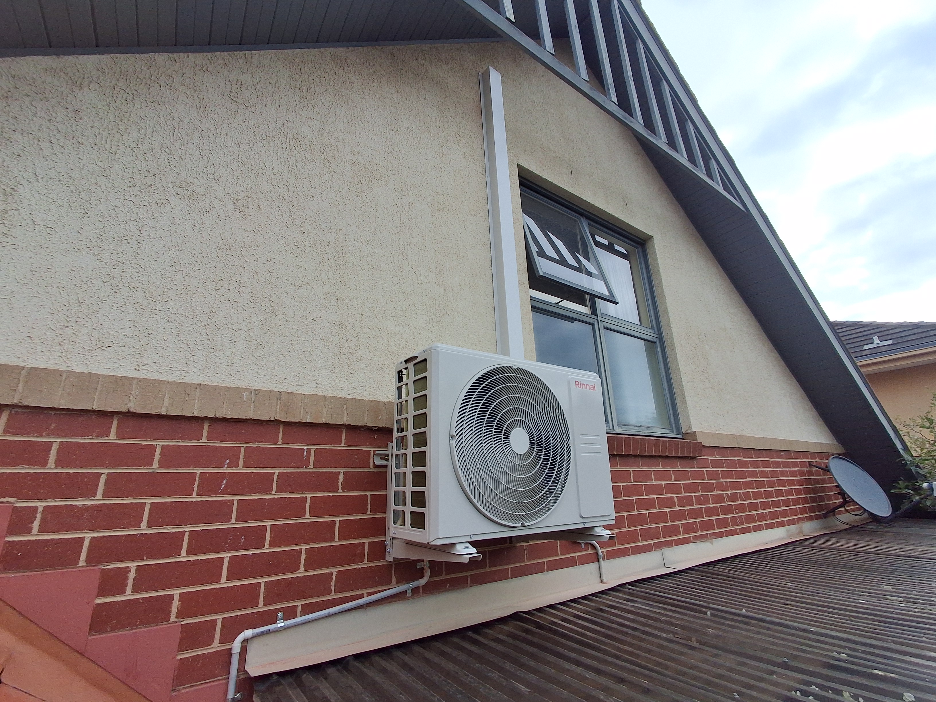 Rinnai outdoor unit mounted on brick home exterior