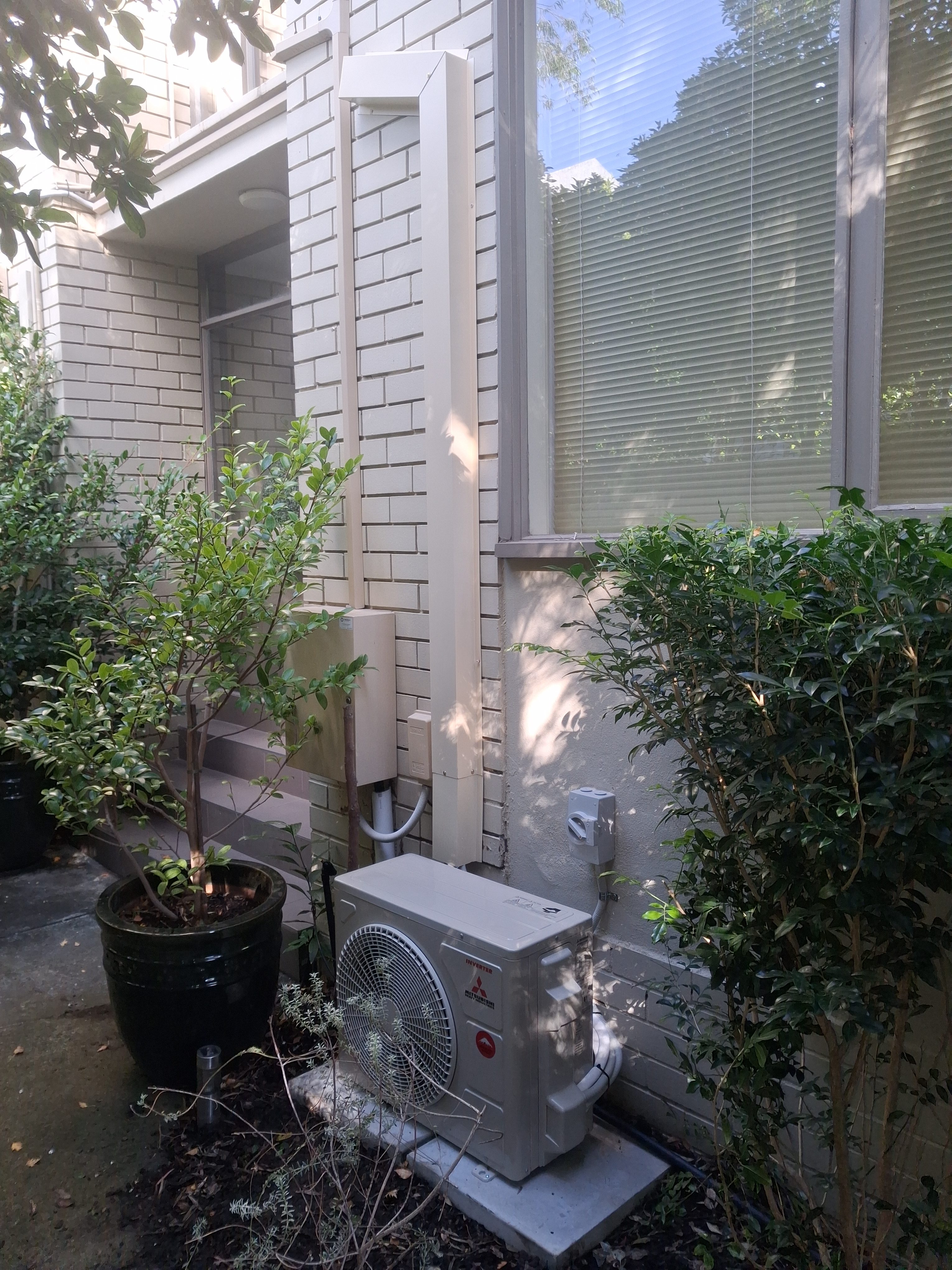 Mitsubishi outdoor cooling unit in garden setting