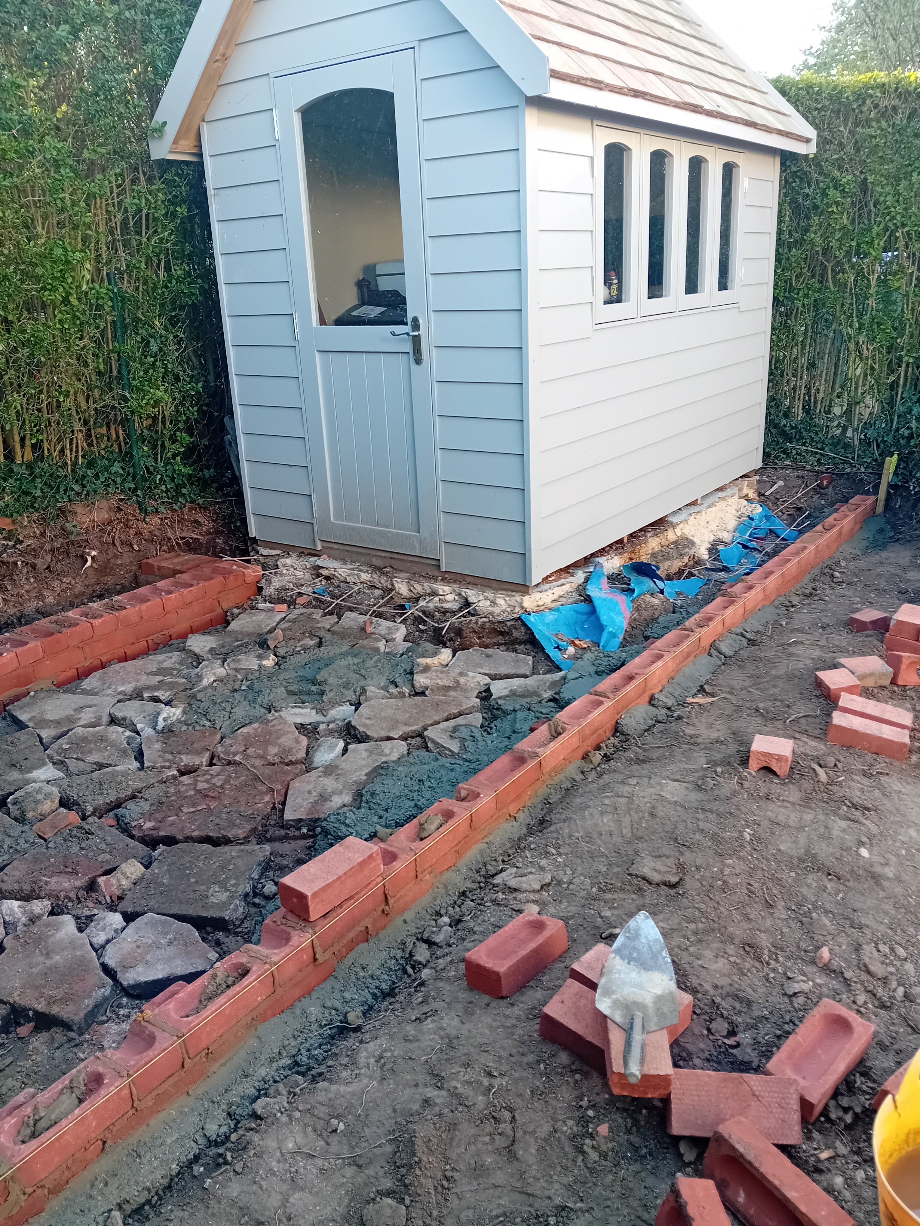 Freshly built summerhouse with new red-brick edged path and crazy paving in a landscaped garden