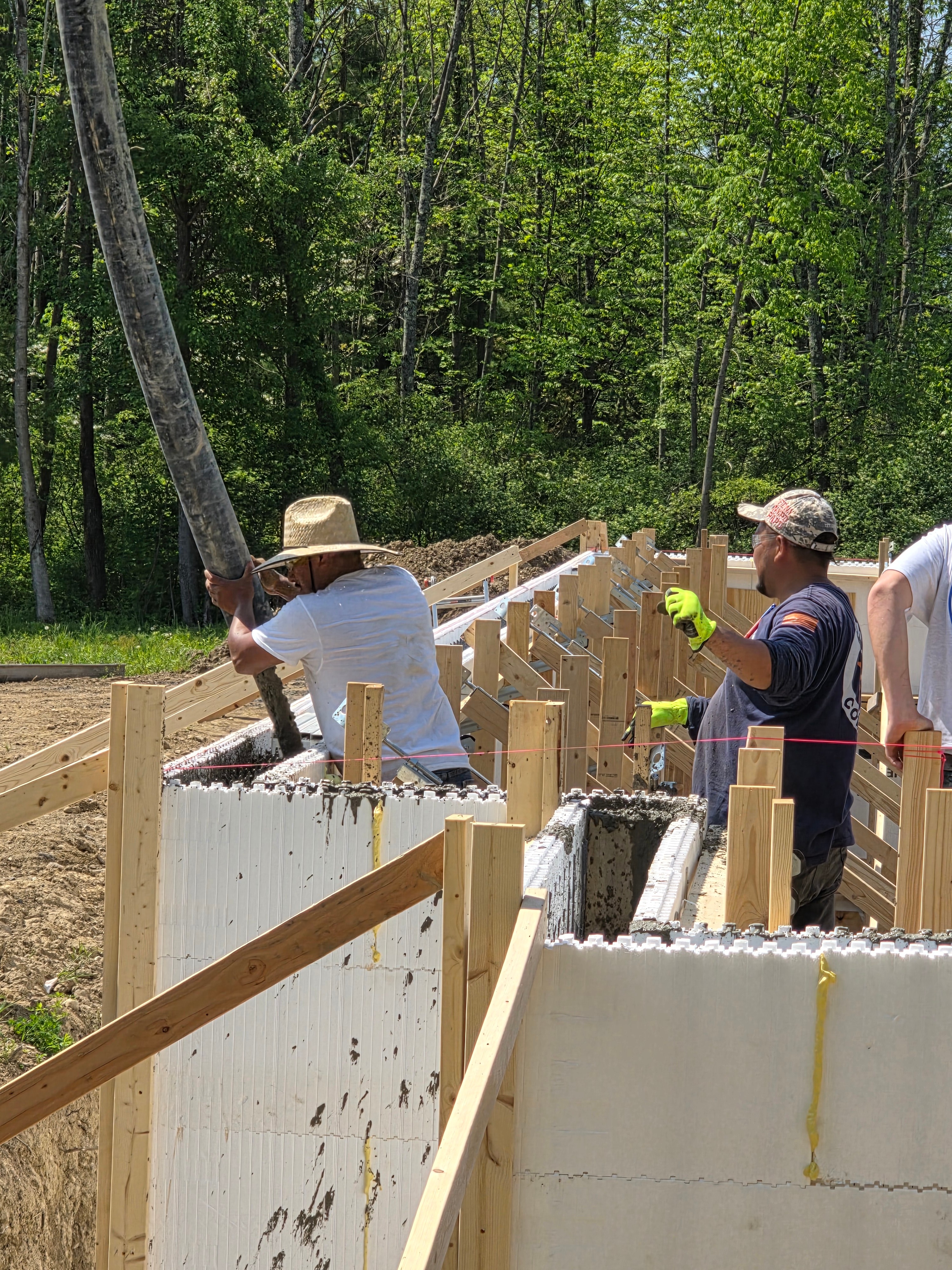 Crew pouring concrete into ICF walls with pump hose