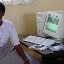 Junger Mann sitzt allein vor einem alten CRT-Computer in der Missionsschule