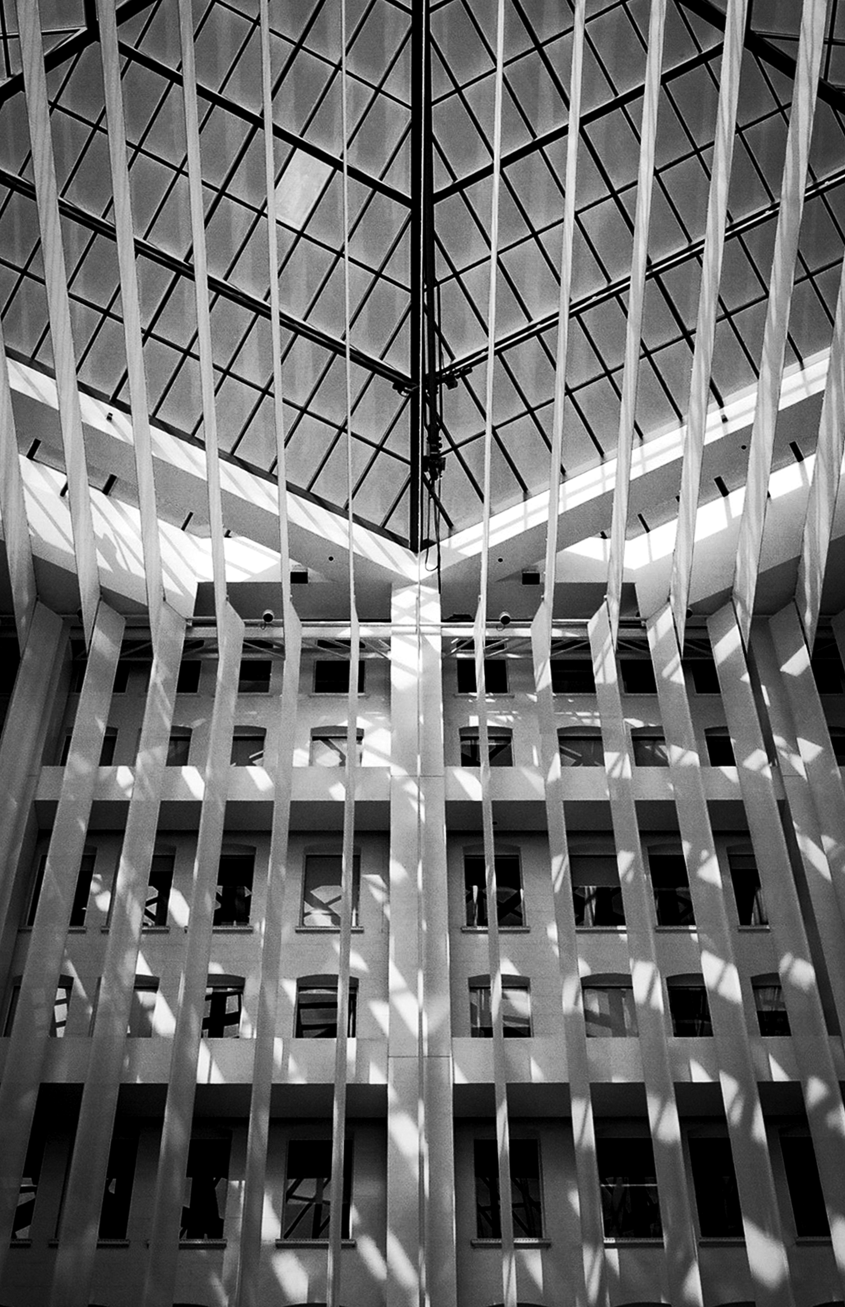 Modernist interior courtyard with symmetrical grid ceiling, dramatic architectural lines and minimalist design