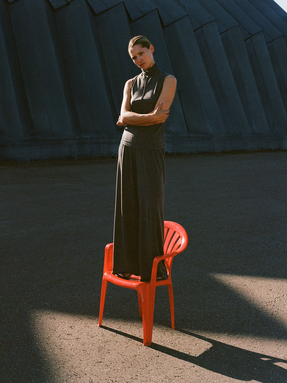 12Storeez — dark grey maxi dress, red plastic chair, dramatic shadows
