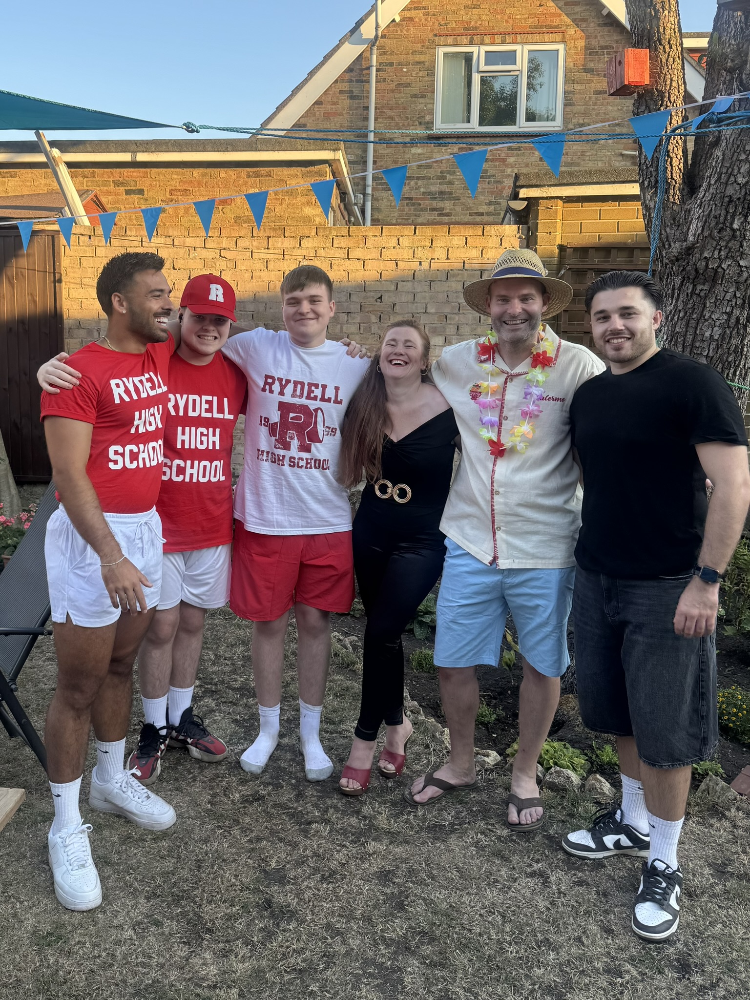 The group posing together in the garden at the Grease-themed party