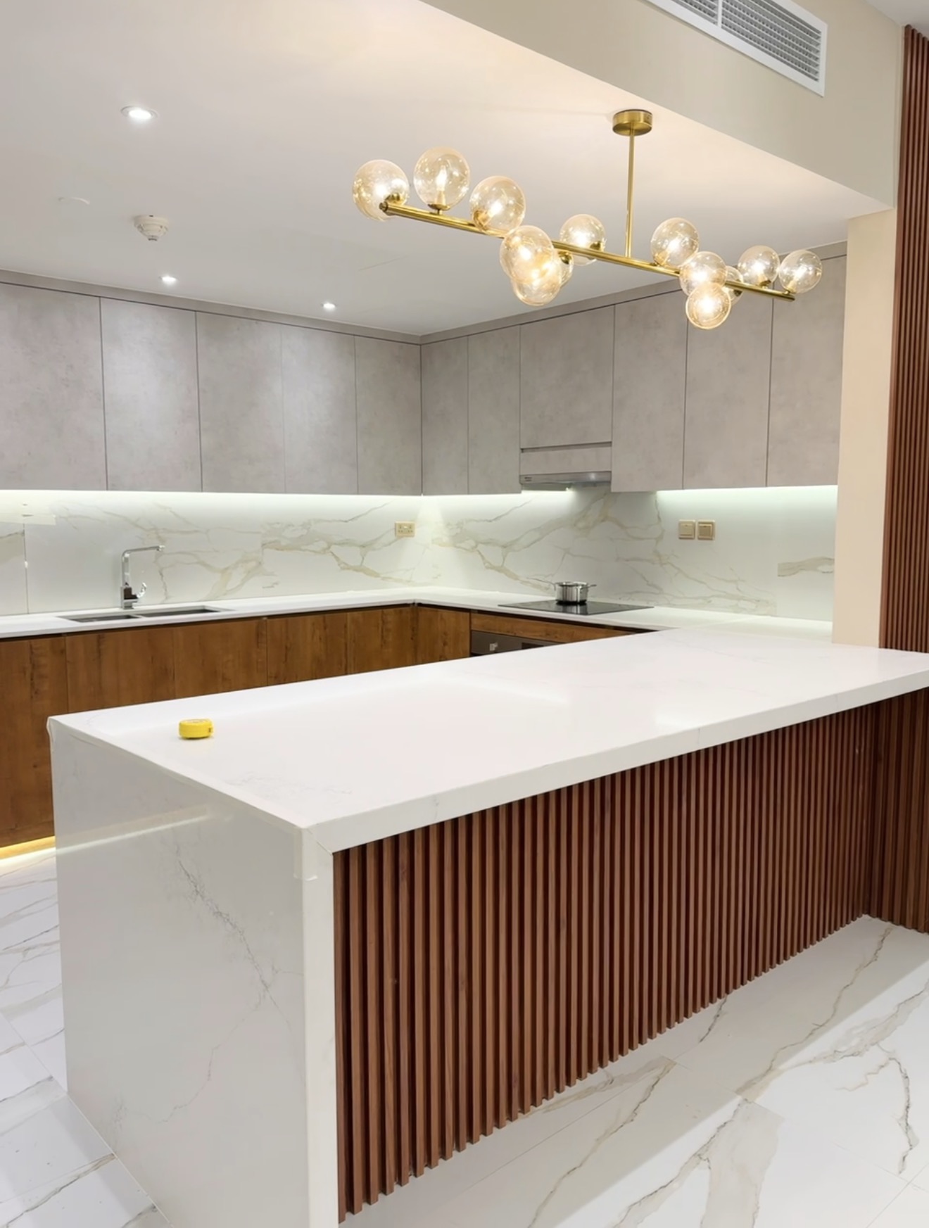 Kitchen with wood slat island and gold chandelier