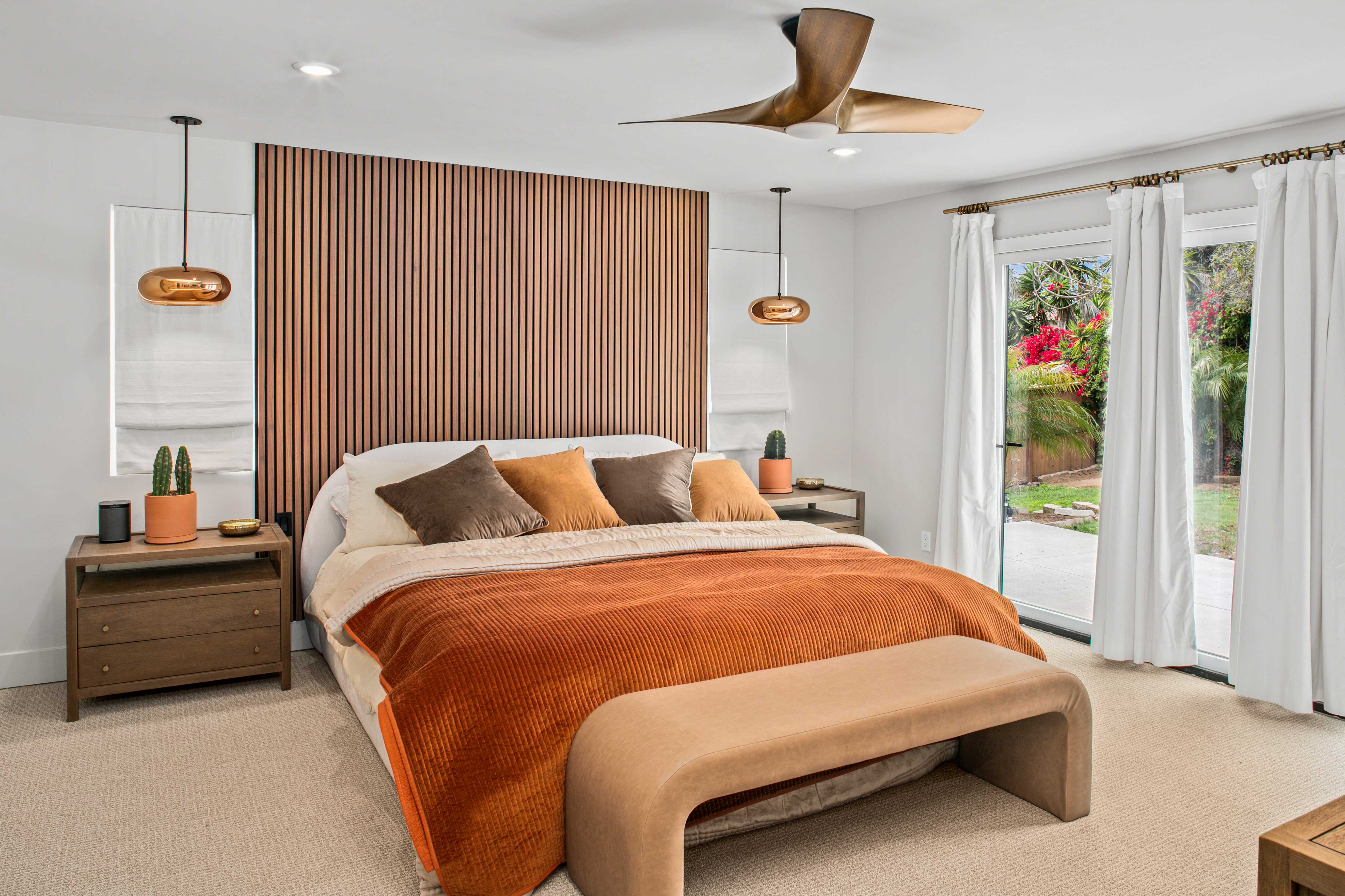 Primary bedroom with wood slat accent wall and brass pendant lights