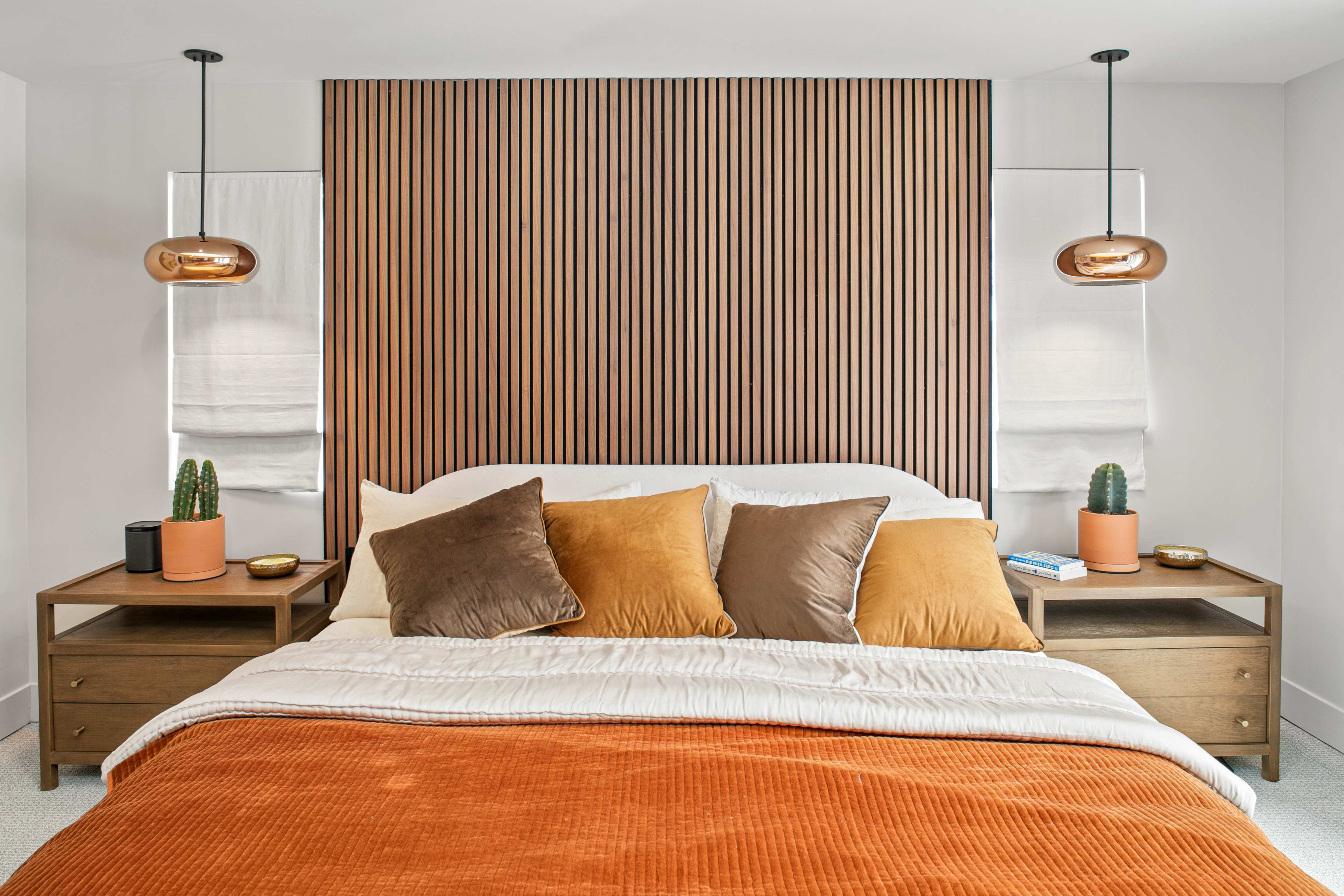 Serene bedroom with wood slat headboard wall and orange velvet bedding