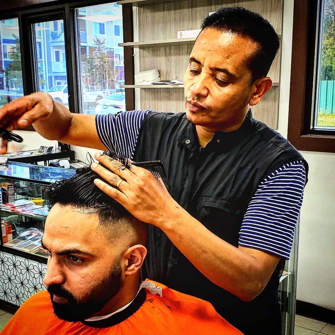 Zed's barber cutting hair with scissors and comb