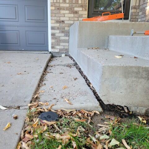 Before: sunken concrete stoop with large gap next to garage door