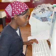 Mädchen mit Kopftuch tippt konzentriert am Computer