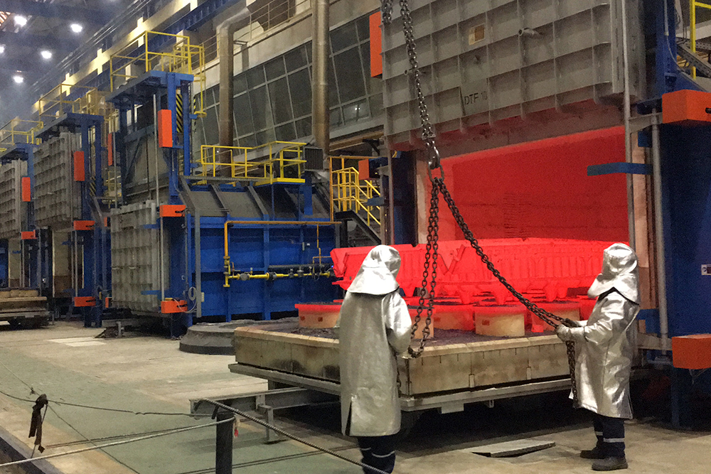 Workers in protective gear operating furnace
