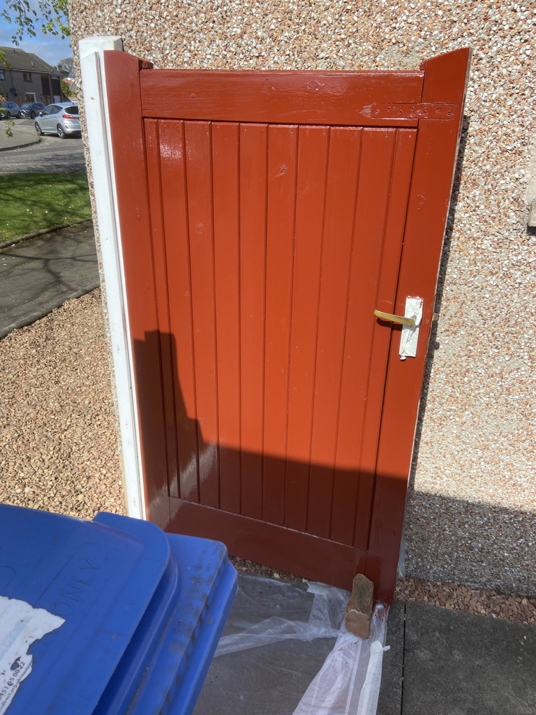Bold red garden gate freshly painted with crisp cream trim