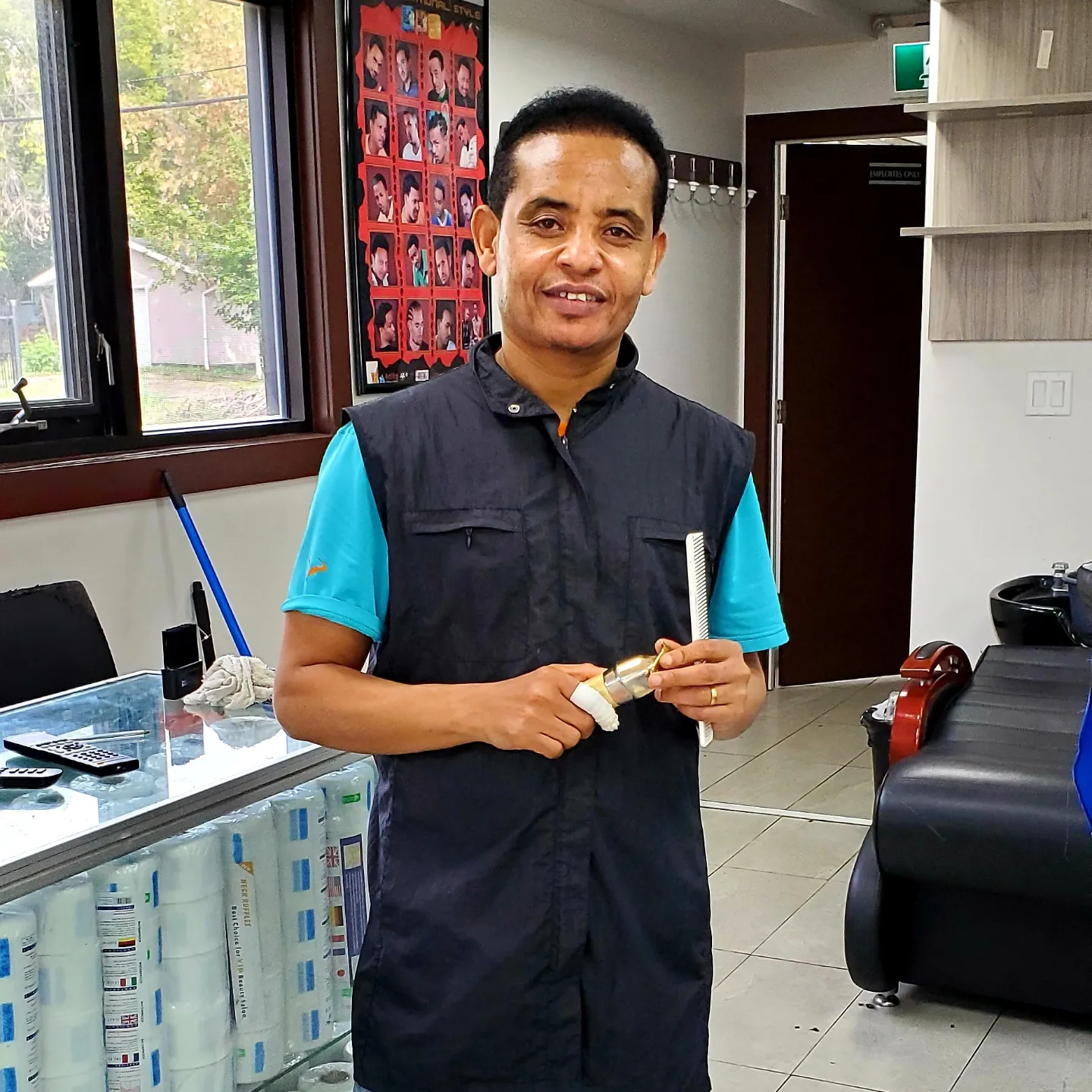 Zed, owner of Zed's Barbershop, holding comb and razor