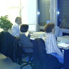 Drei Personen abends an Computerarbeitsplätzen, blau beleuchtet