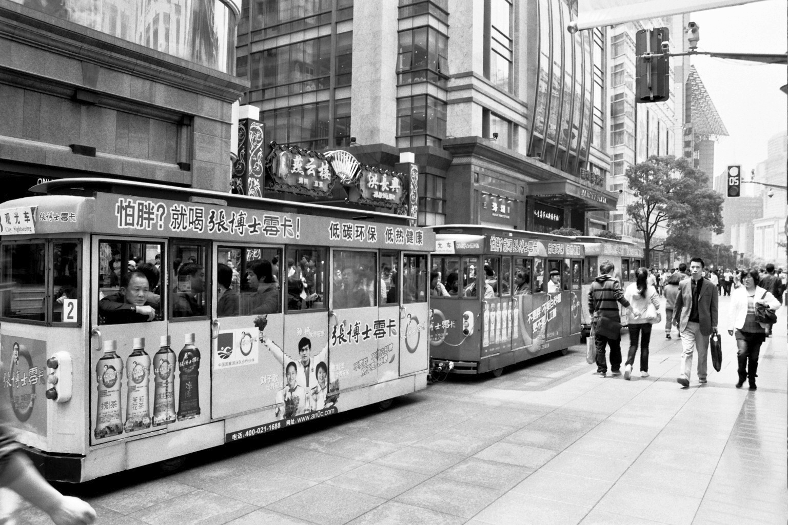 Tourist trams on busy pedestrian shopping street with colorful advertisements