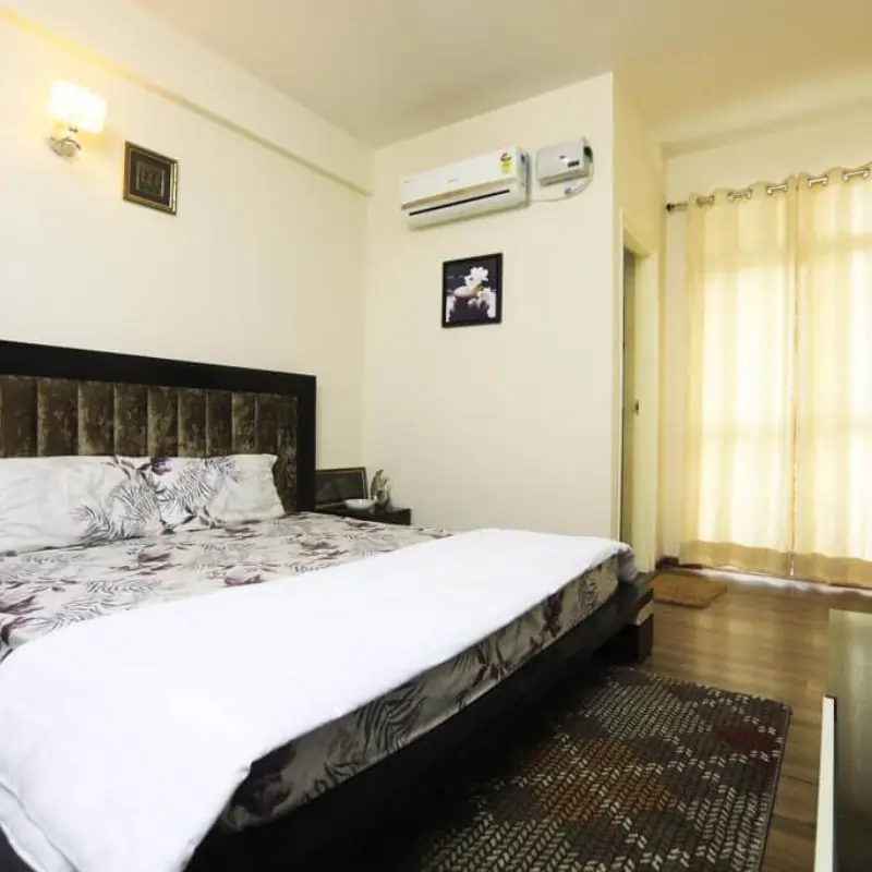 Furnished bedroom inside a Wave Dream Homes apartment with AC and curtains