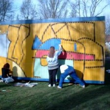 Jugendliche malen gemeinsam ein Wandbild am Container
