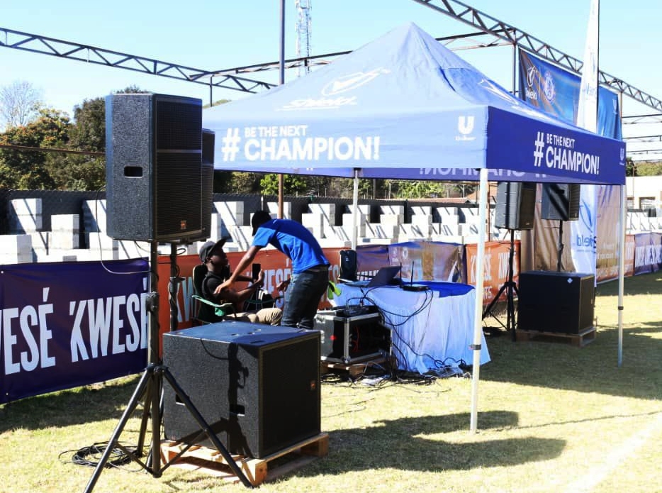 Outdoor event with projection screen, lighting setup, and professional staging