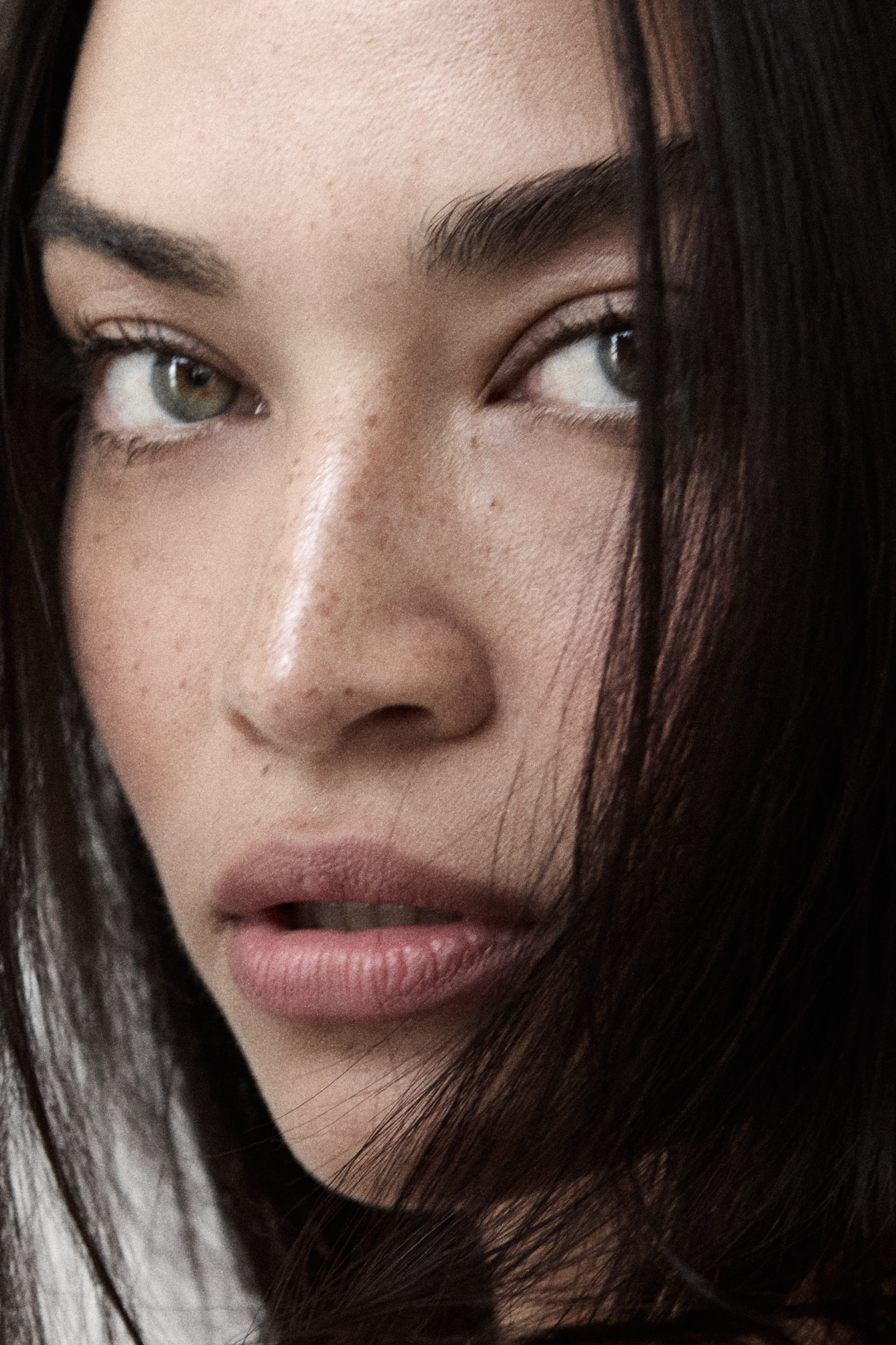 Close-up beauty portrait with dramatic lighting and natural freckles