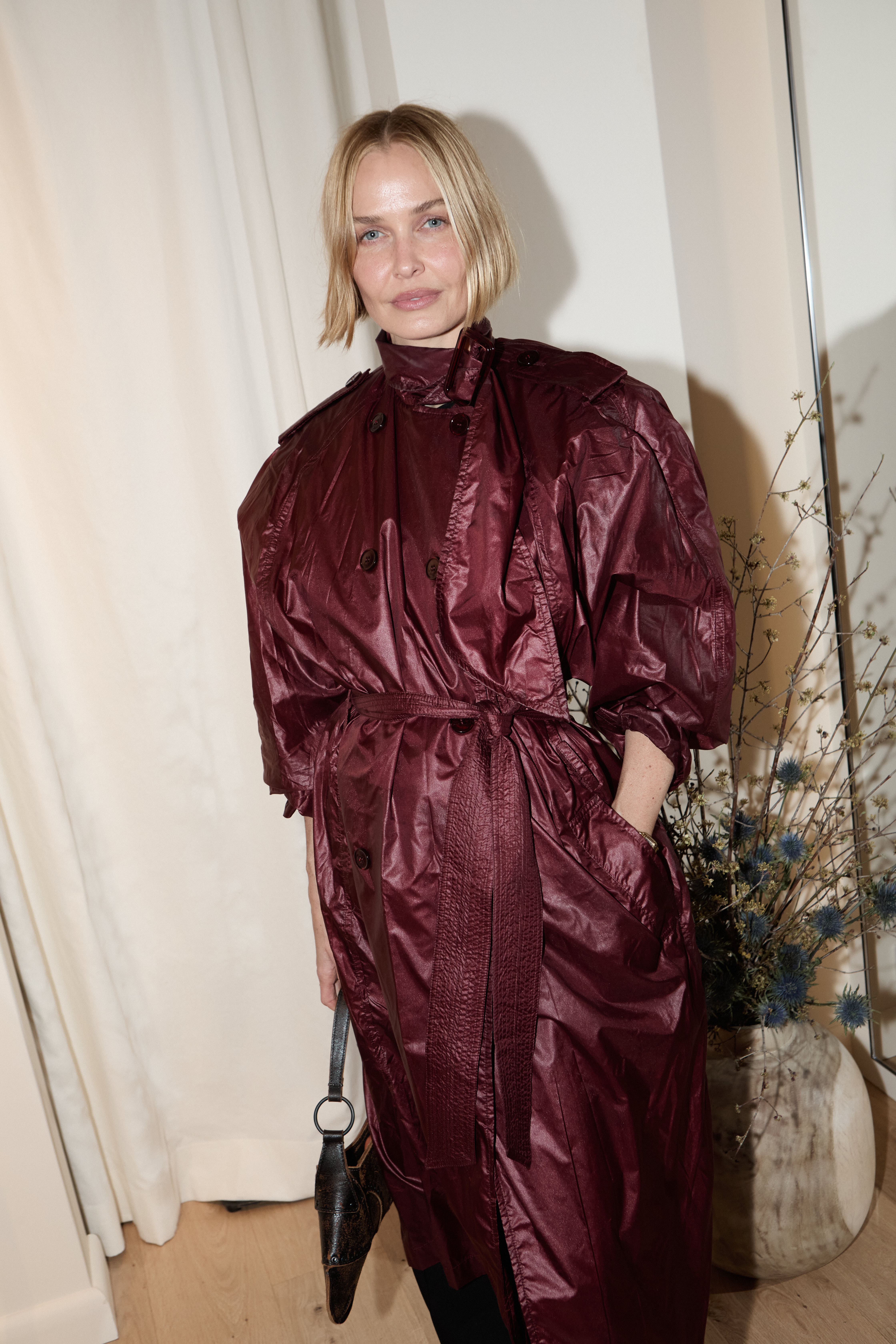 Blonde woman in a glossy burgundy patent trench coat