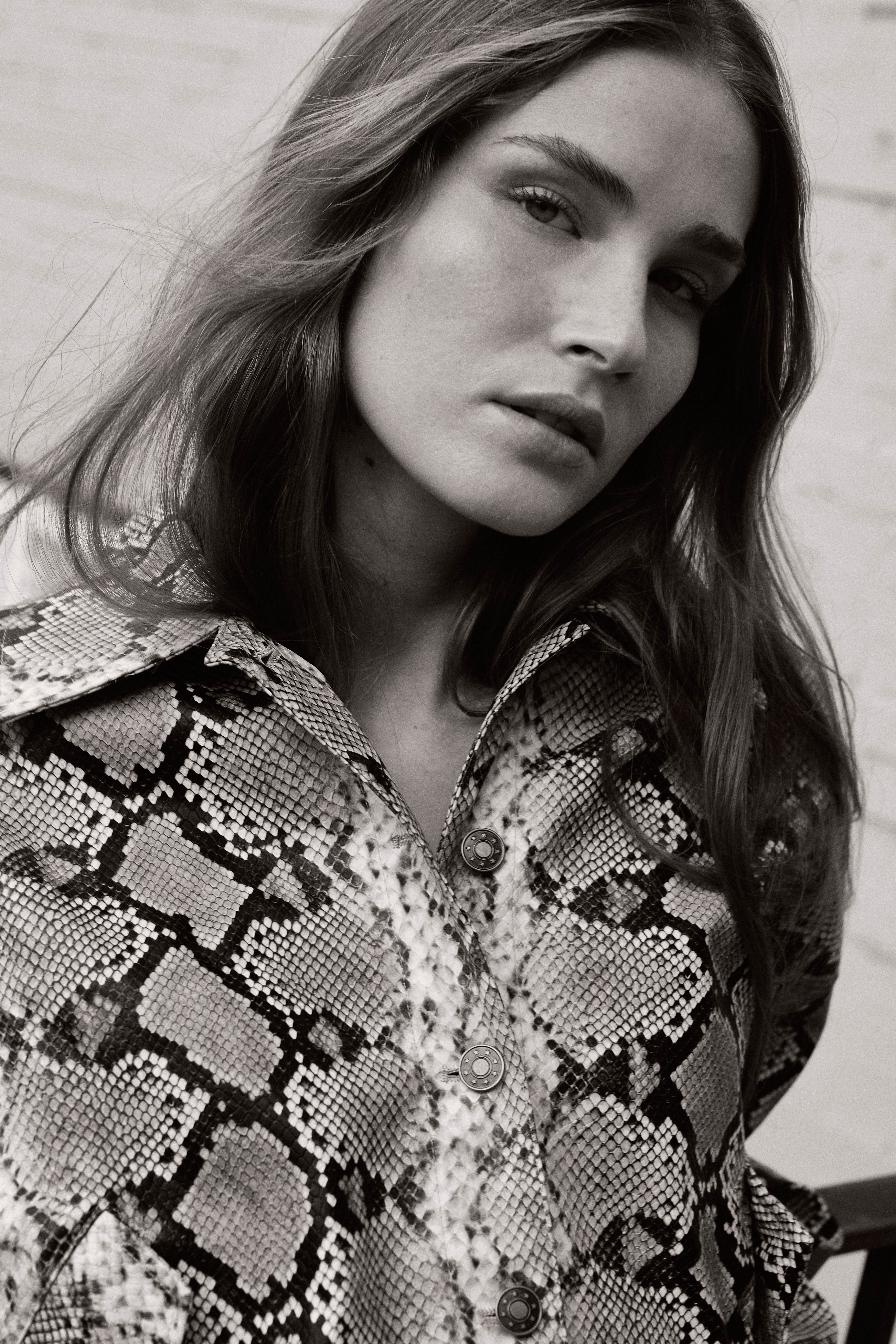 Black and white close-up portrait of a model in a snakeskin-print jacket