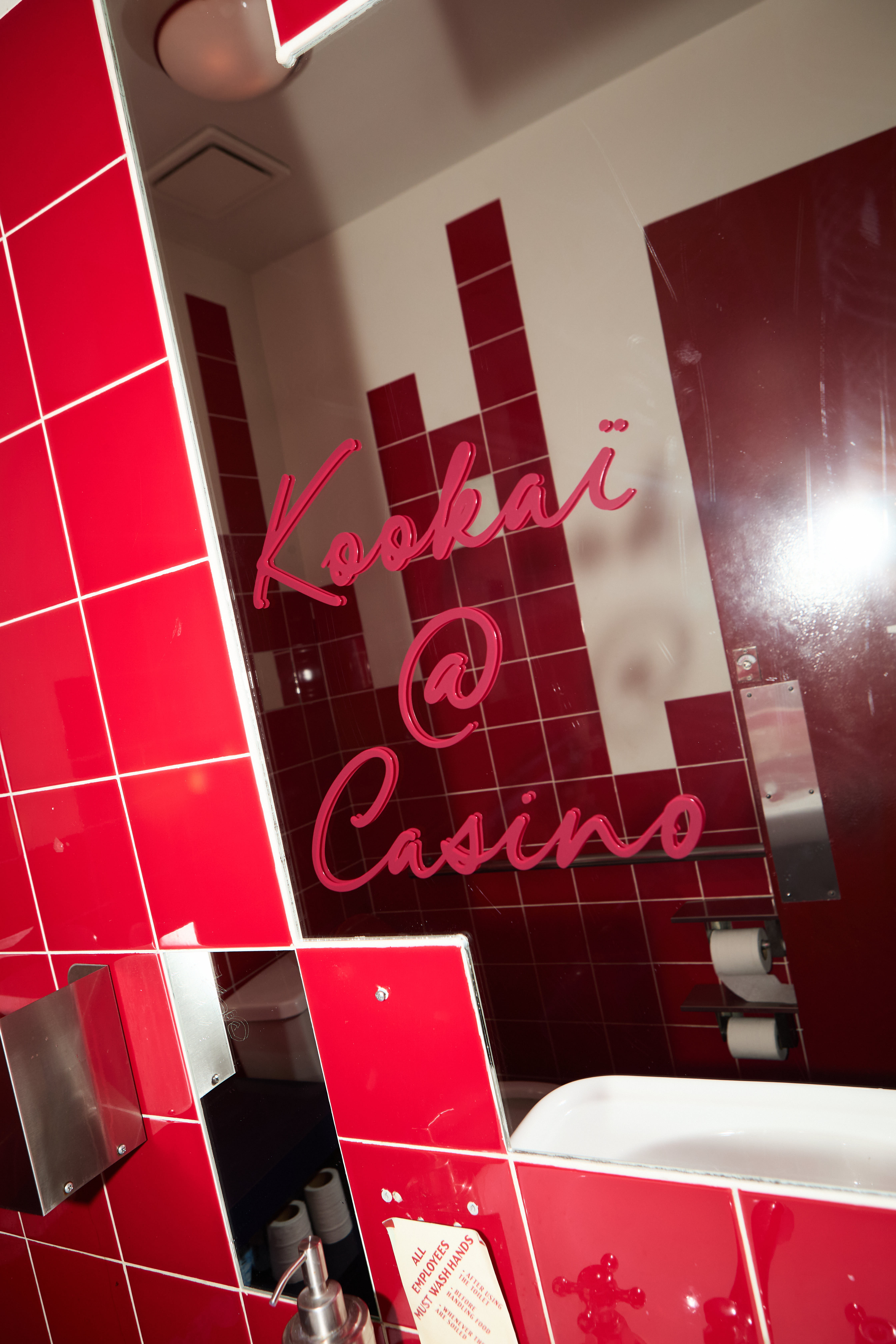 Red-tiled restroom mirror with Kookai at Casino written in red script
