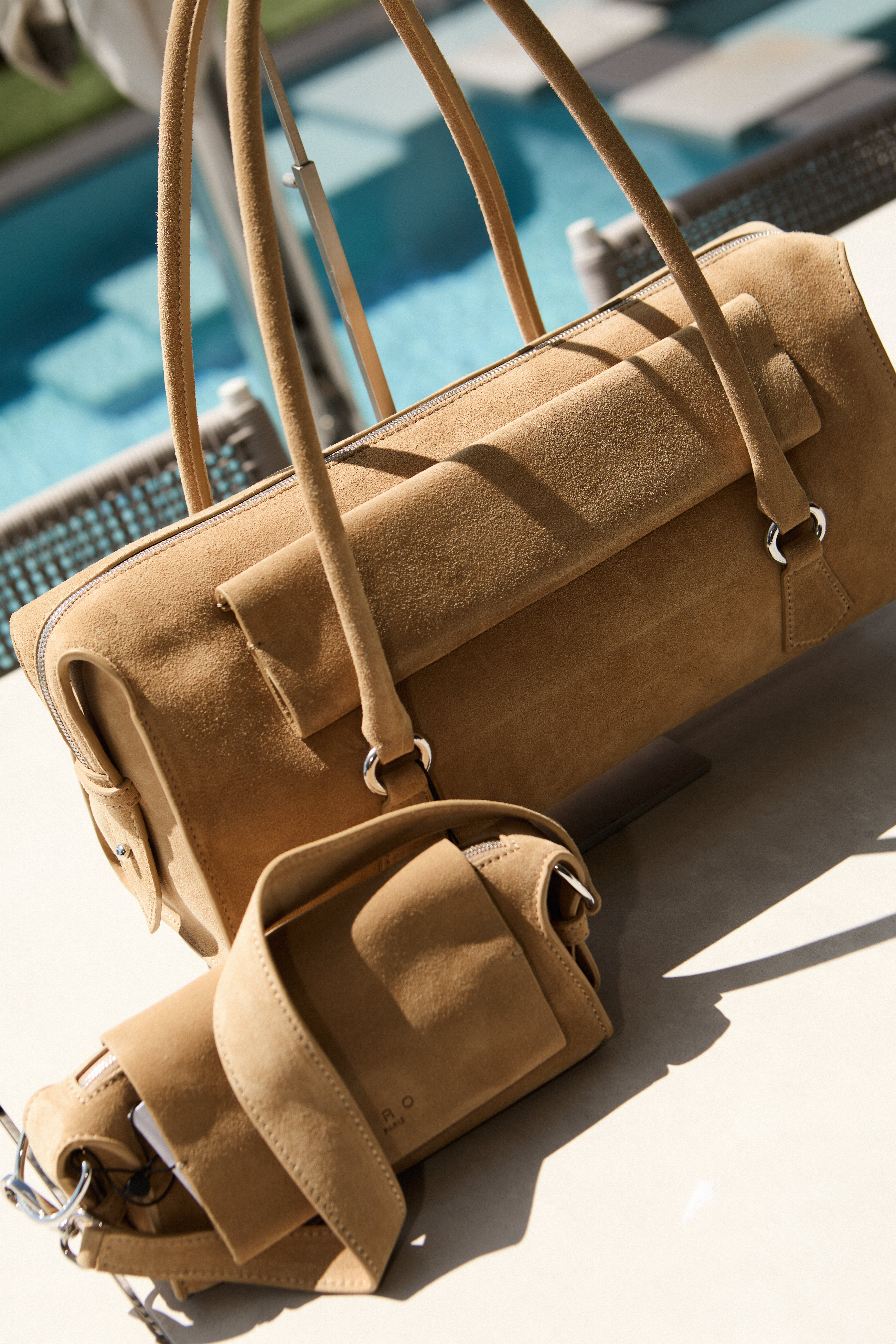Tan suede IRO bags styled poolside in sunlight