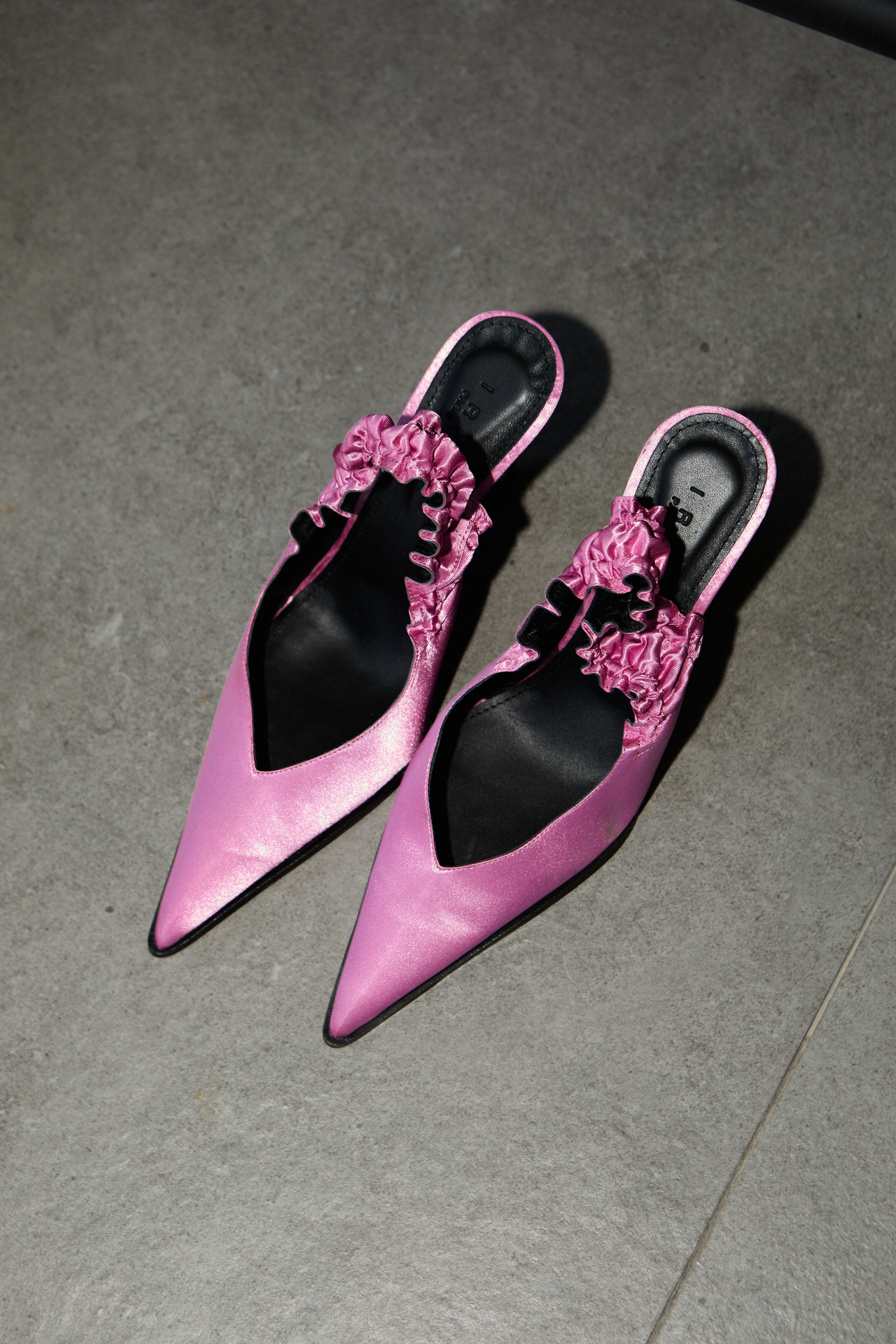 Pink satin ruffle pointed-toe slingback heels on concrete