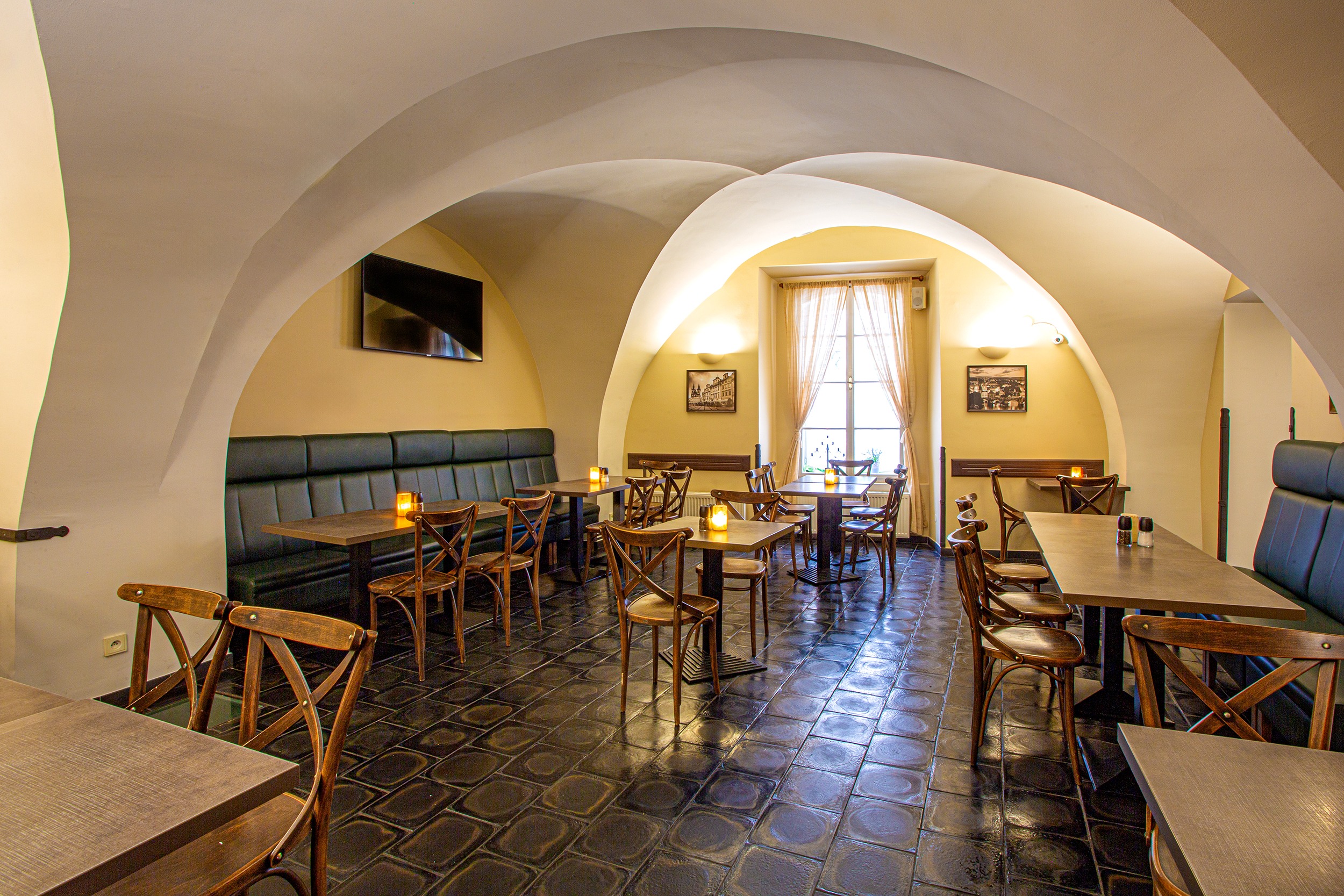 Historický interiér restaurace s klenbami a svíčkami