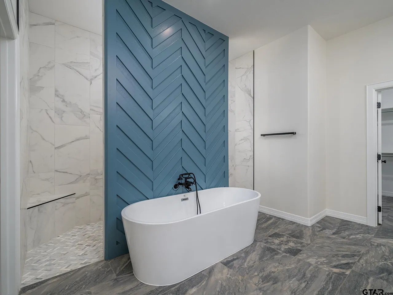 Master bath with blue chevron accent wall and freestanding tub