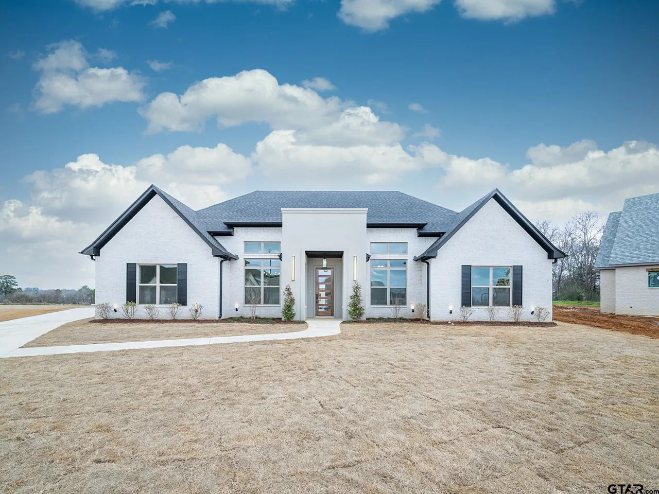 White brick modern farmhouse exterior with dark shutters