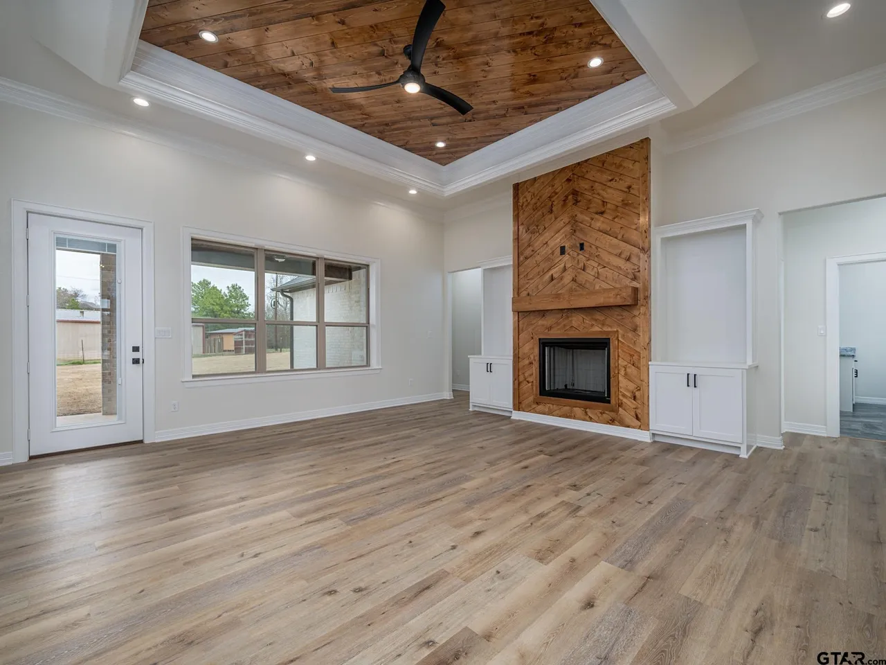 Great room with tray ceiling and chevron wood fireplace surround