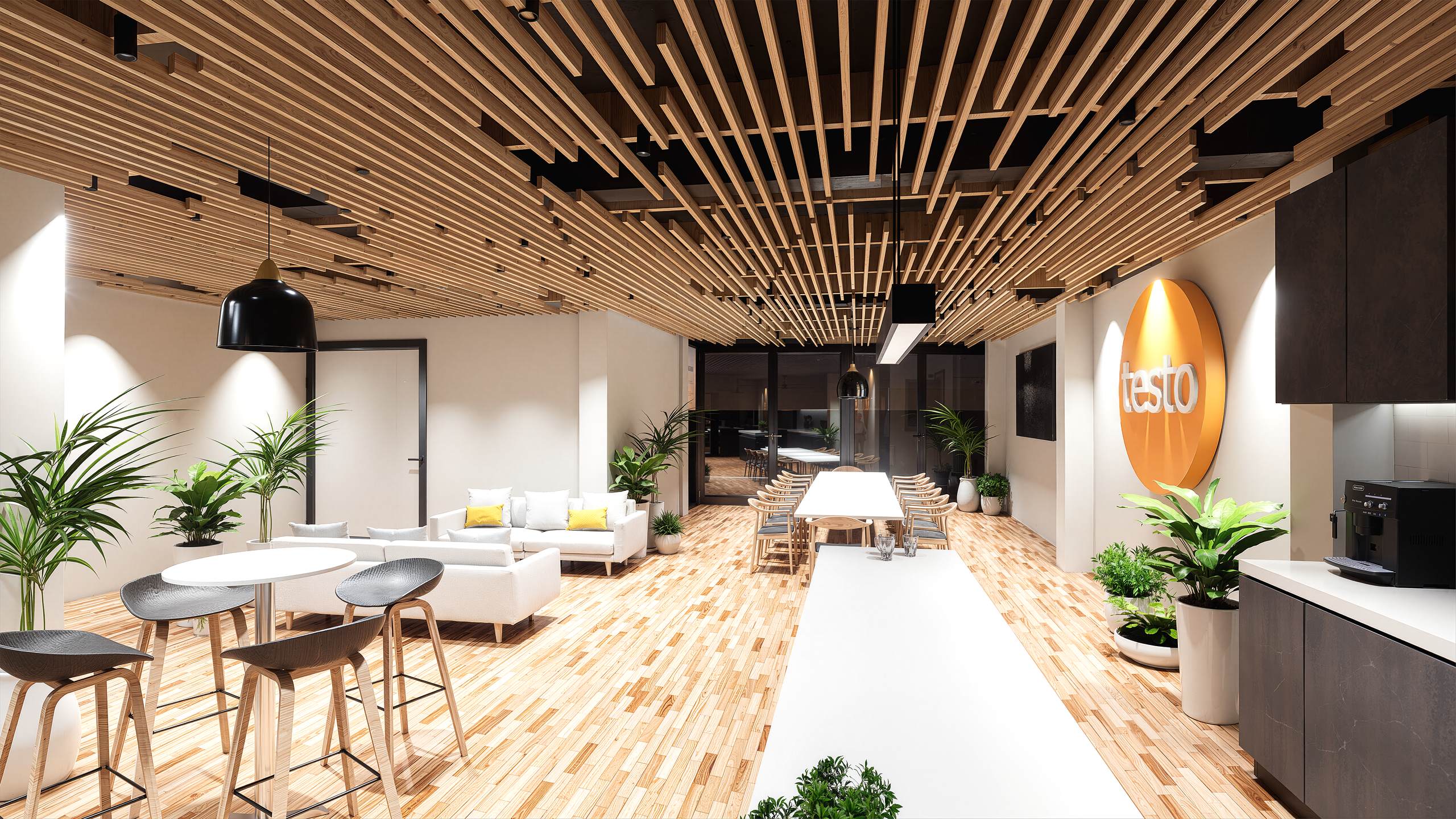 Espacio abierto con sofas, mesa de reunion larga, logo Testo, plantas y kitchenette
